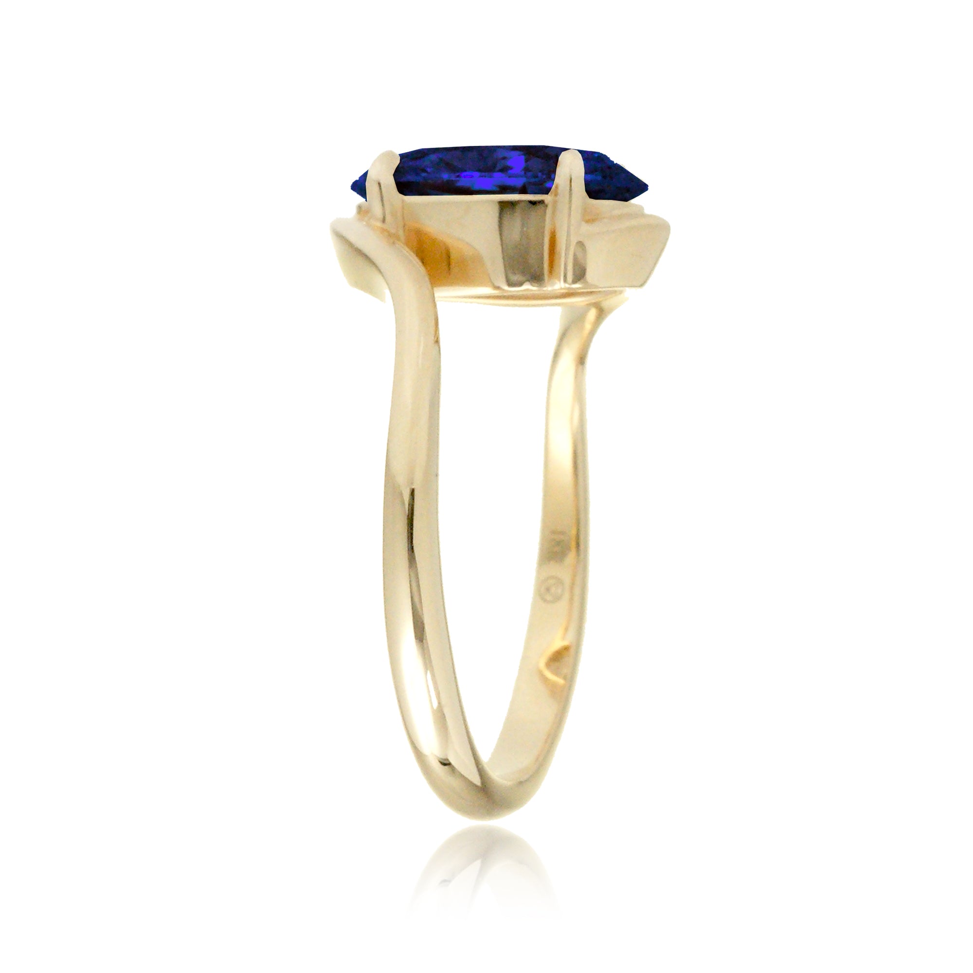 Elegant bypass-style oval sapphire ring with polished yellow gold shank