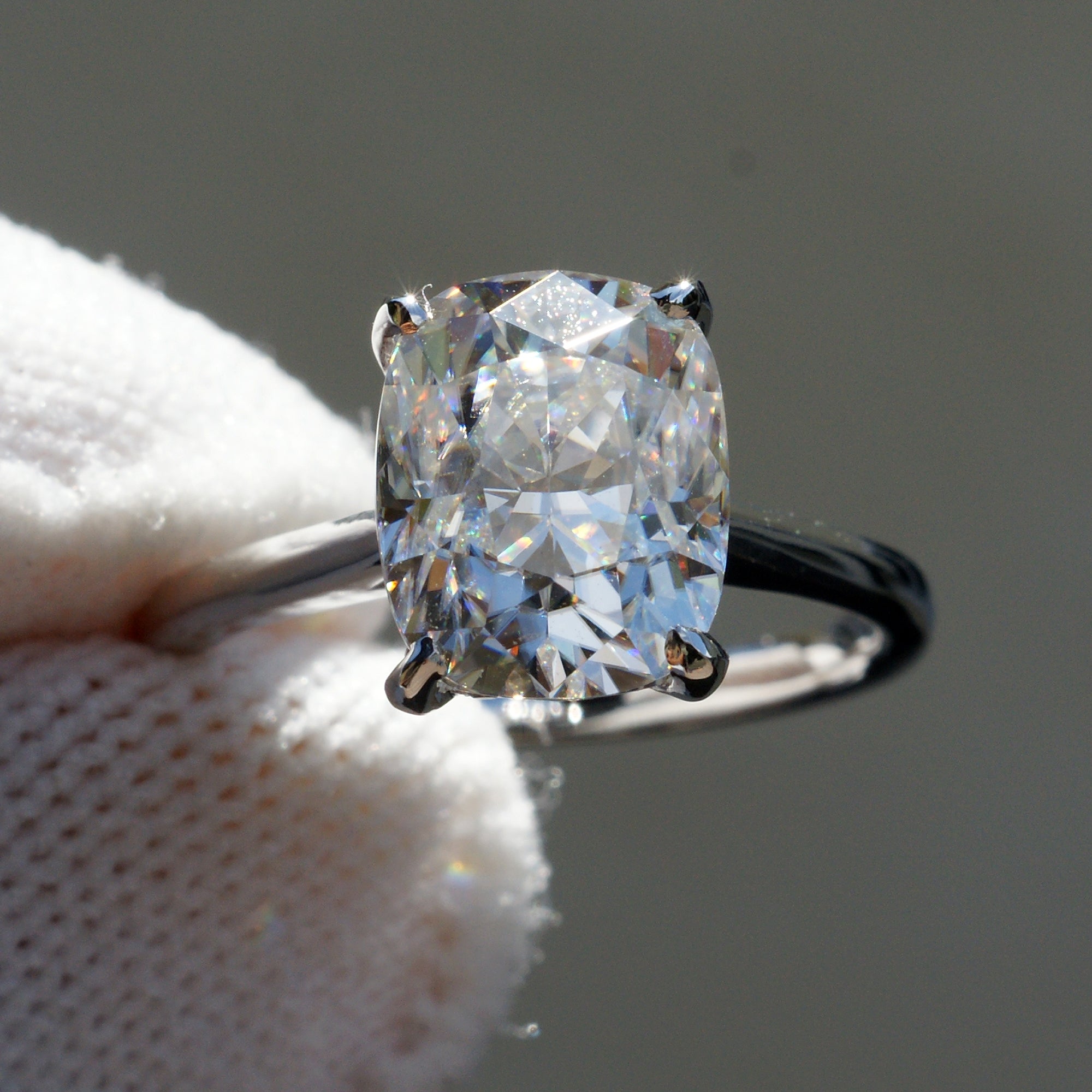 Cushion solitaire moissanite engagement ring in white gold with a hidden halo