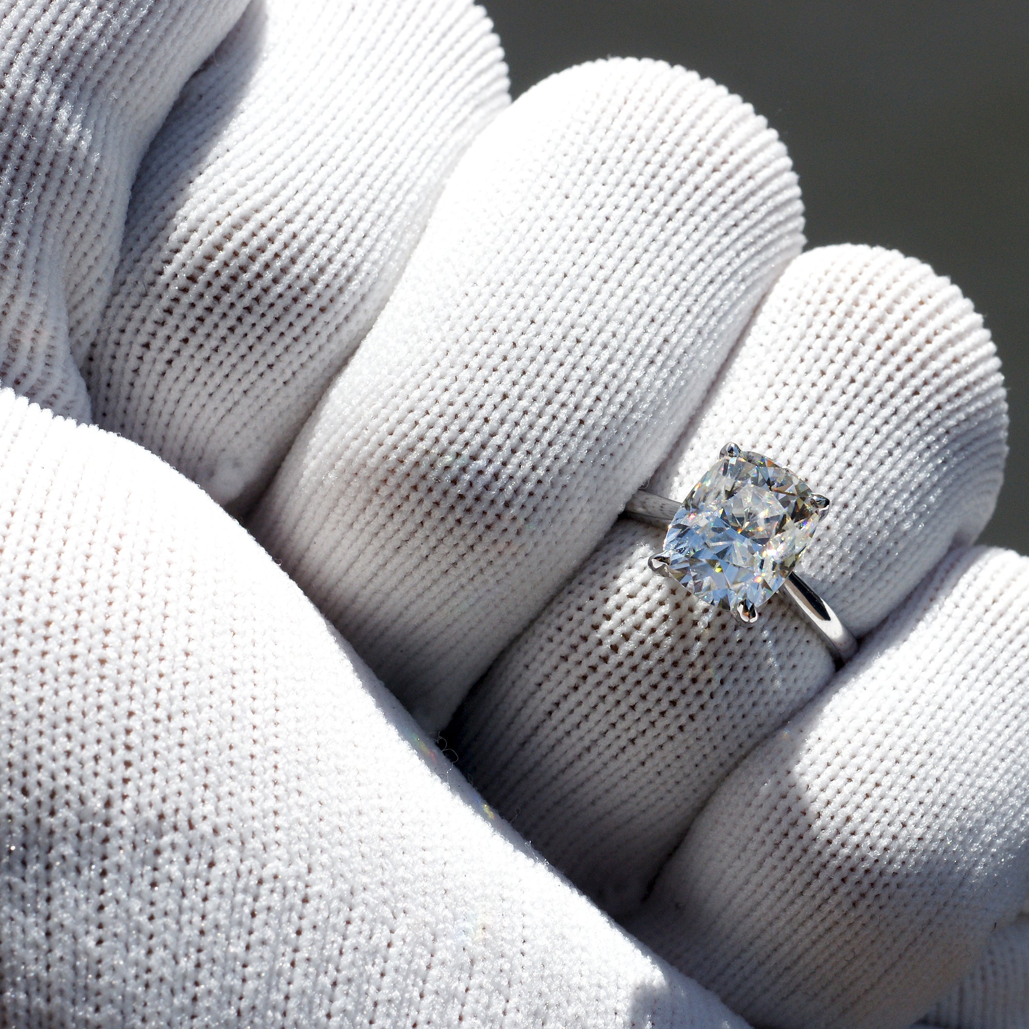 Cushion solitaire moissanite engagement ring in white gold with a hidden halo