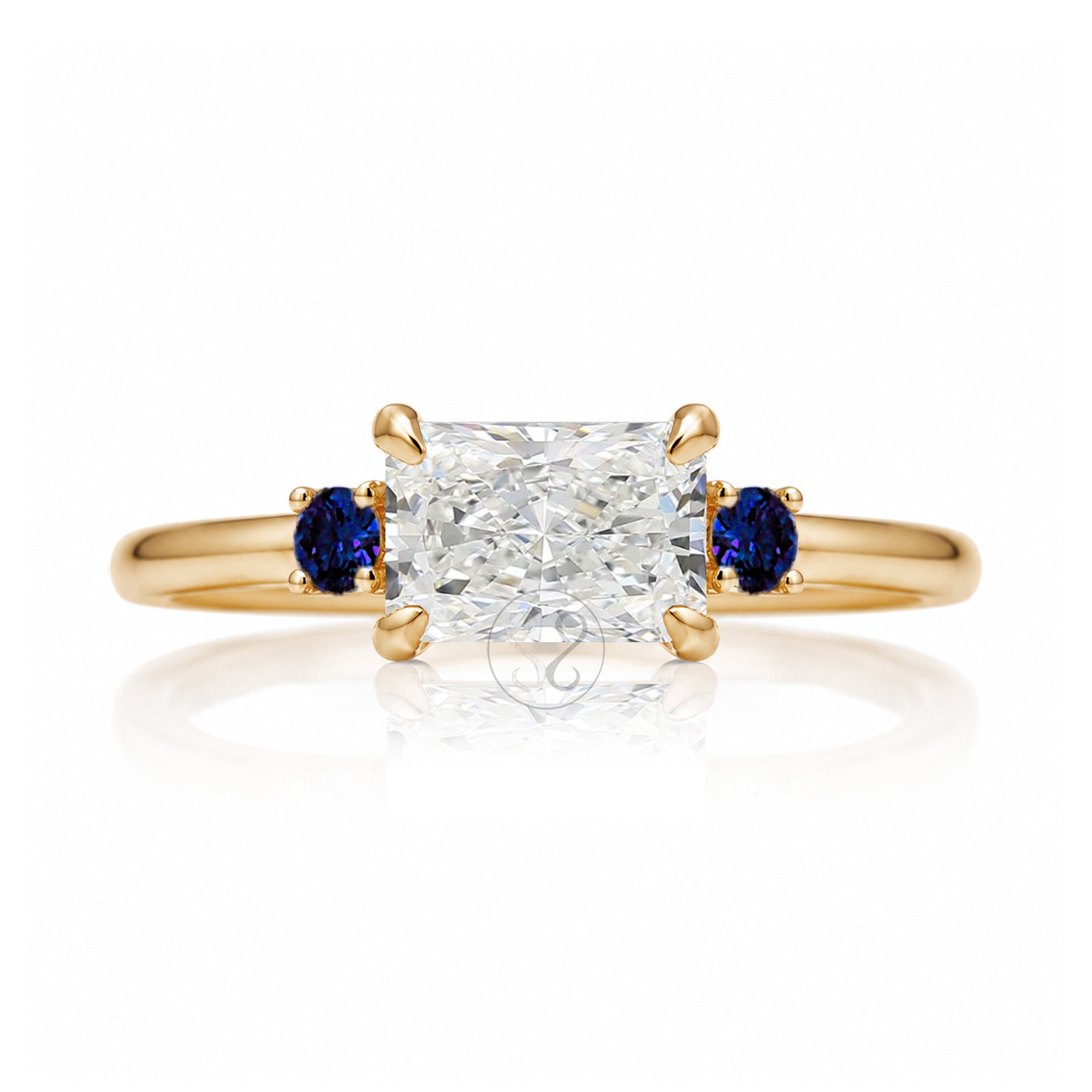 east-west radiant cut lab-grown diamond threestone ring with side blue sapphires yellow gold