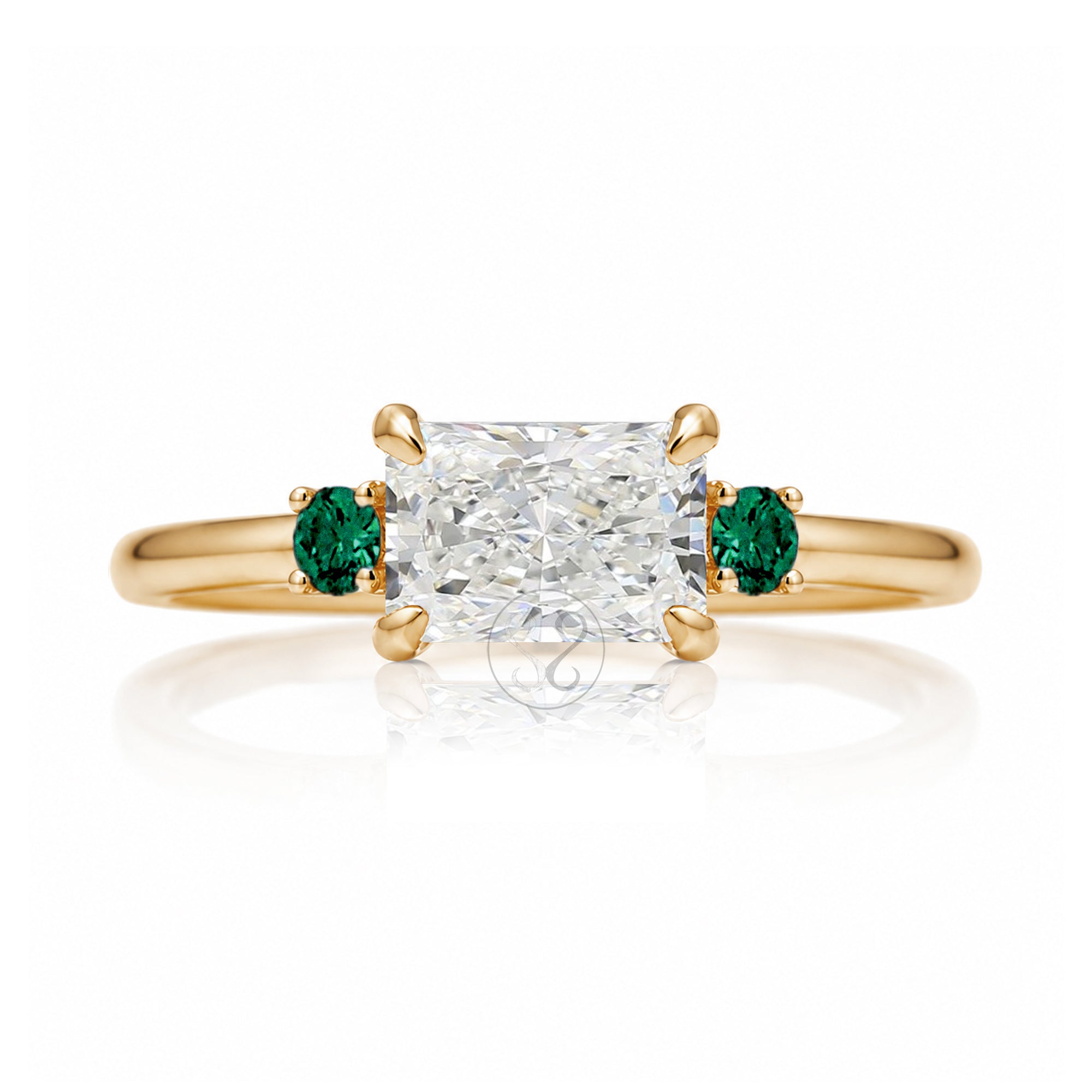 east-west radiant cut lab-grown diamond threestone ring with green emerald yellow gold