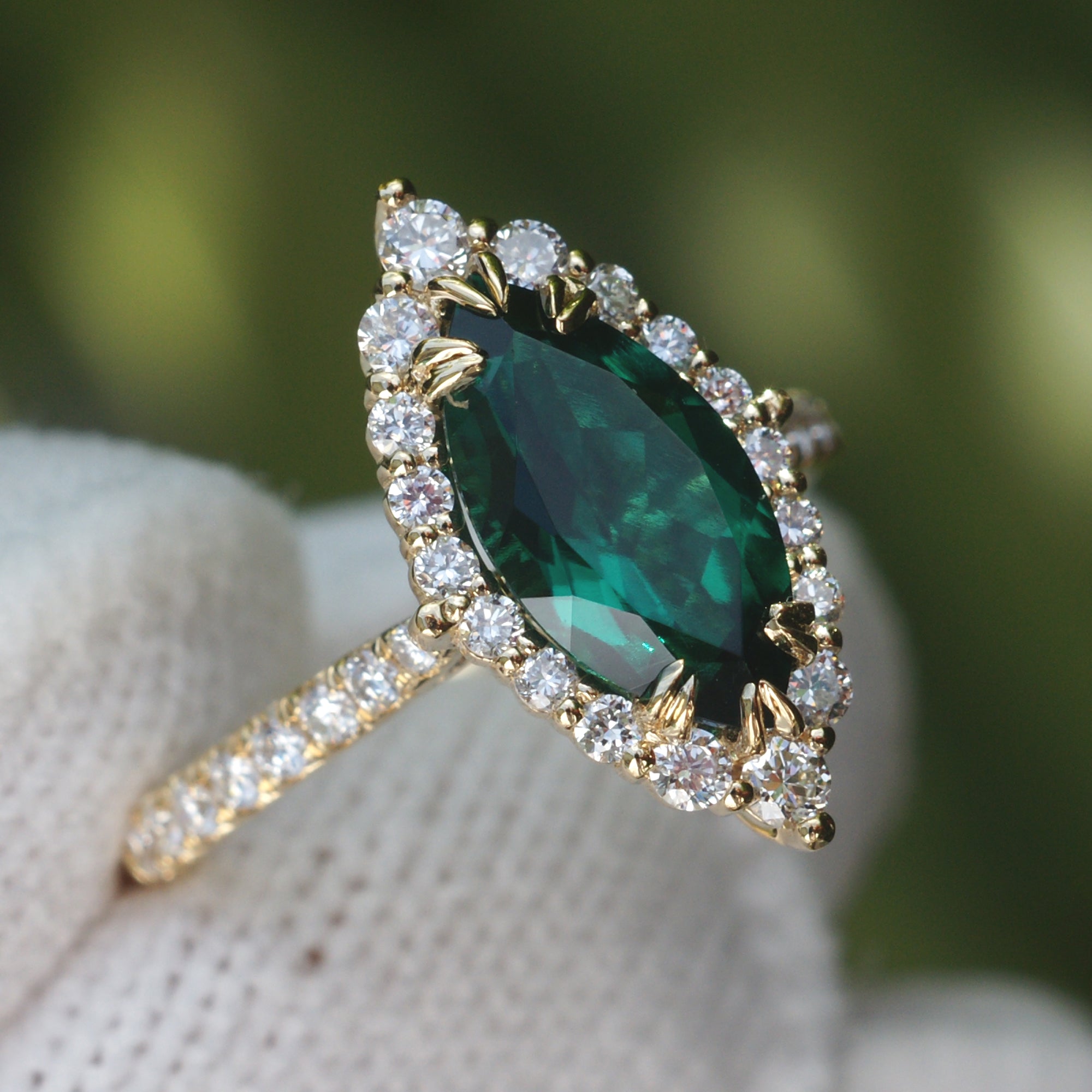 Marquise emerald with diamond halo gradual diamond band yellow gold close up view