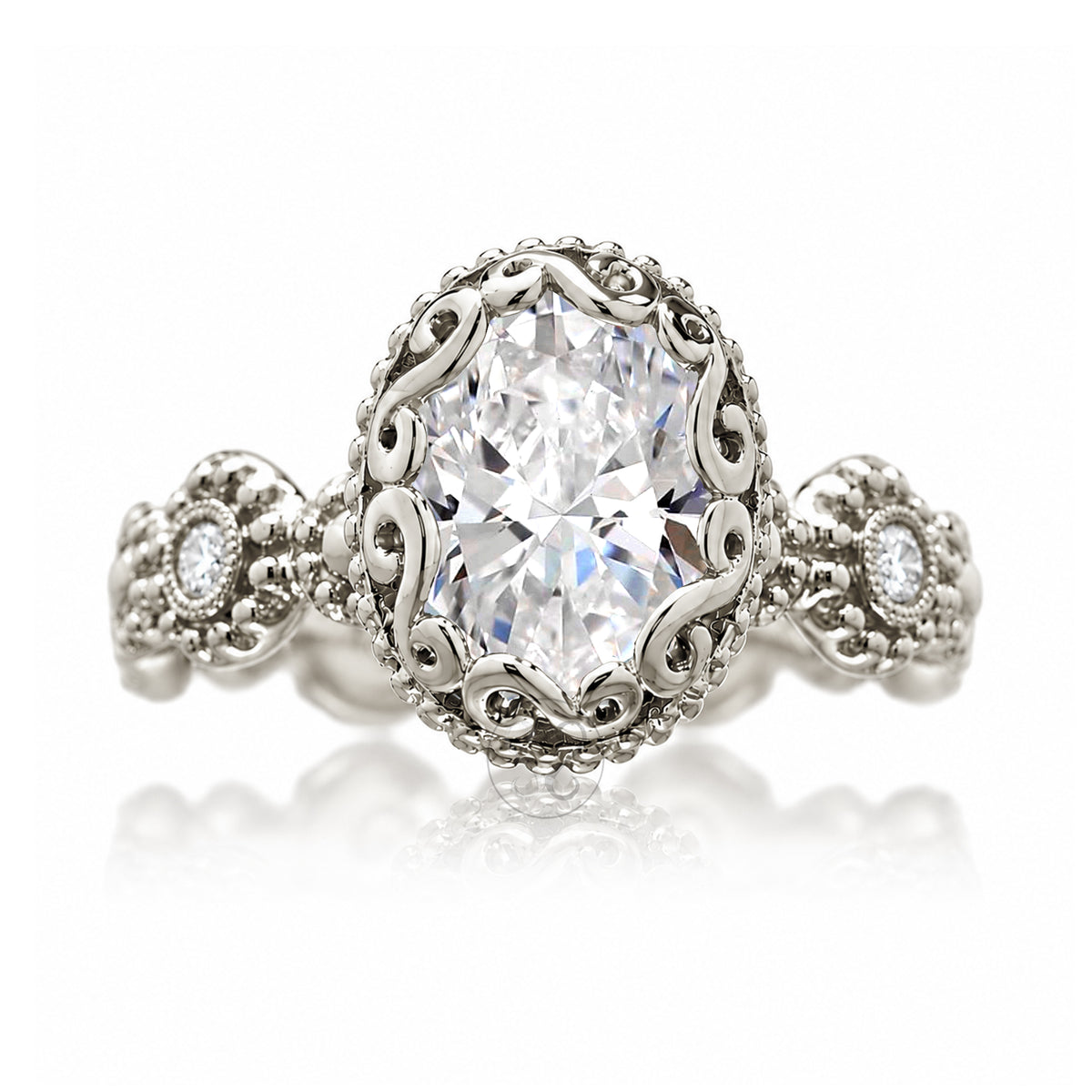 An ornate silver-tone ring featuring a large oval-cut clear center stone surrounded by a decorative filigree halo, with smaller accent stones on the band, shown on a white background with a soft reflection.
