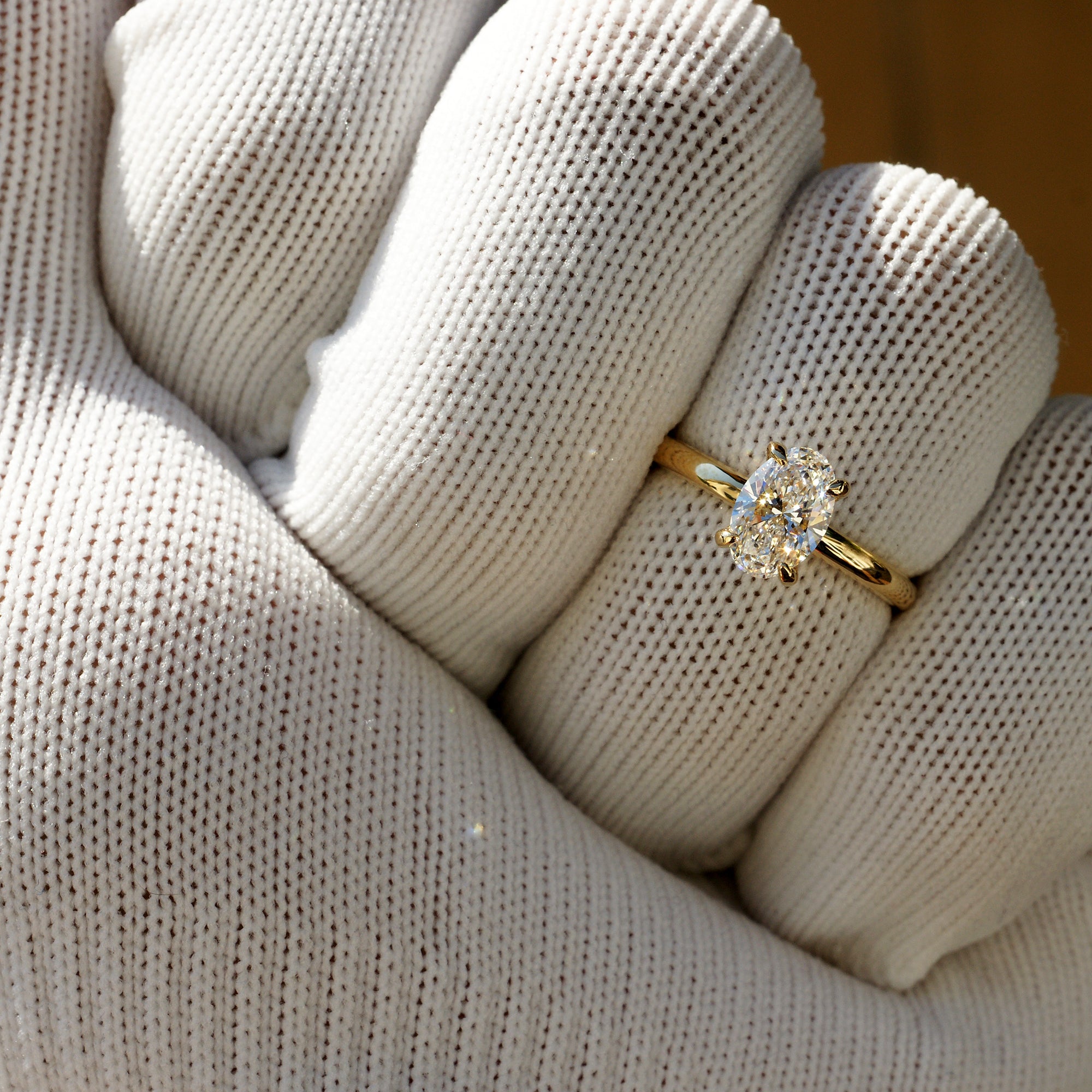 Finger view of 1.04ct oval lab-grown diamond engagement ring in 18k yellow gold with high-polish solid band
