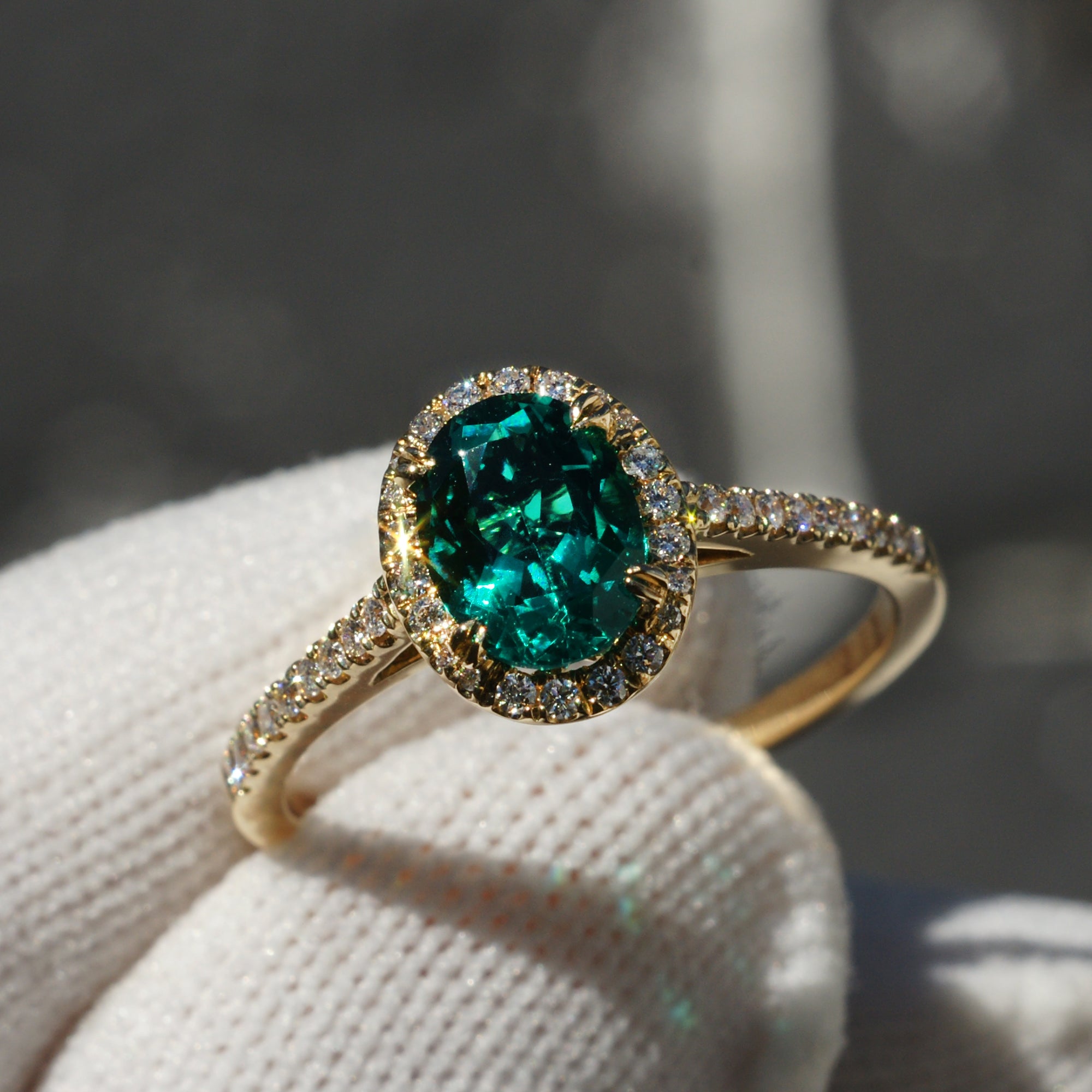 Oval cut green emerald 8x6mm engagement ring with a diamond halo in yellow gold