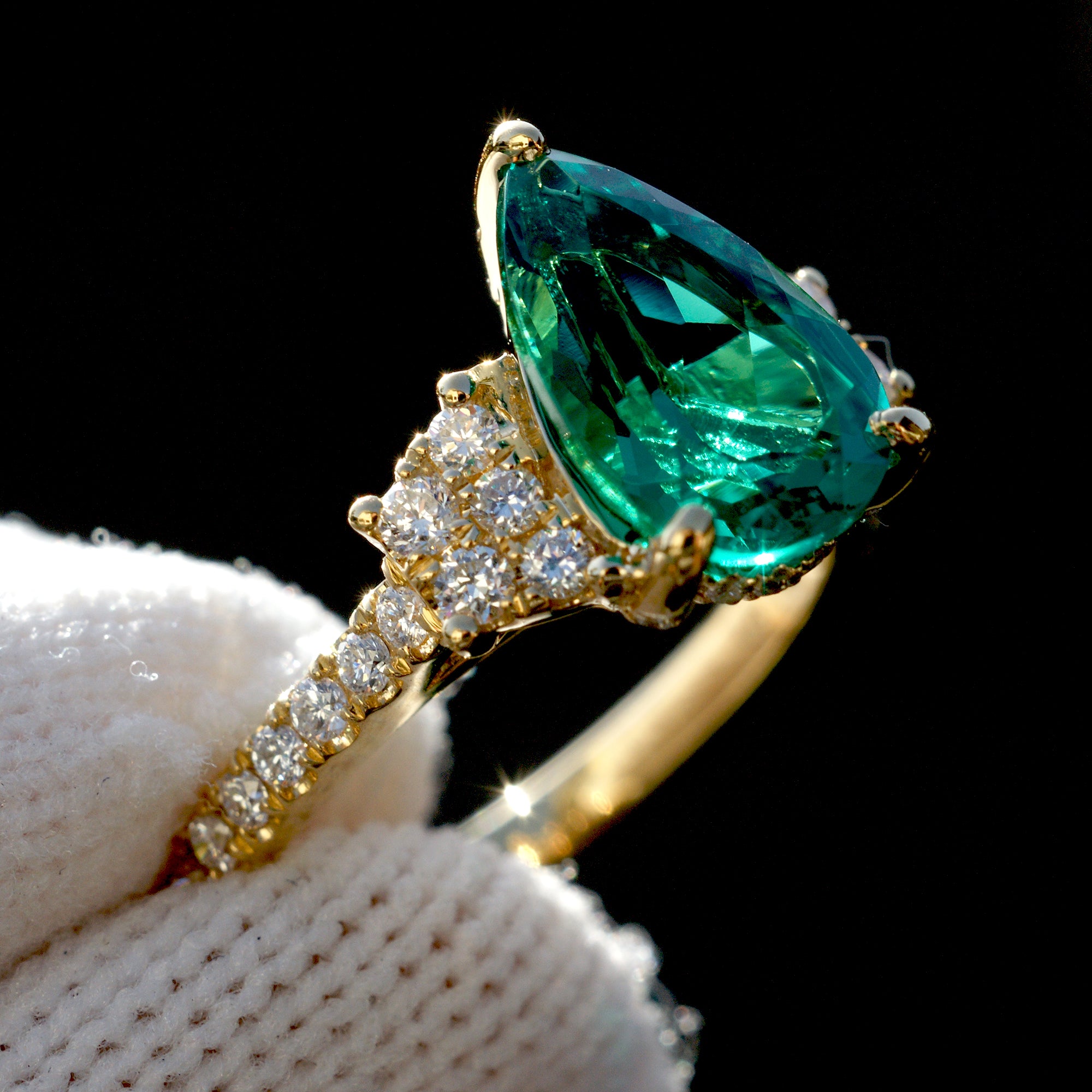 Pear emerald three stone ring with trapezoid side diamond shape in yellow gold