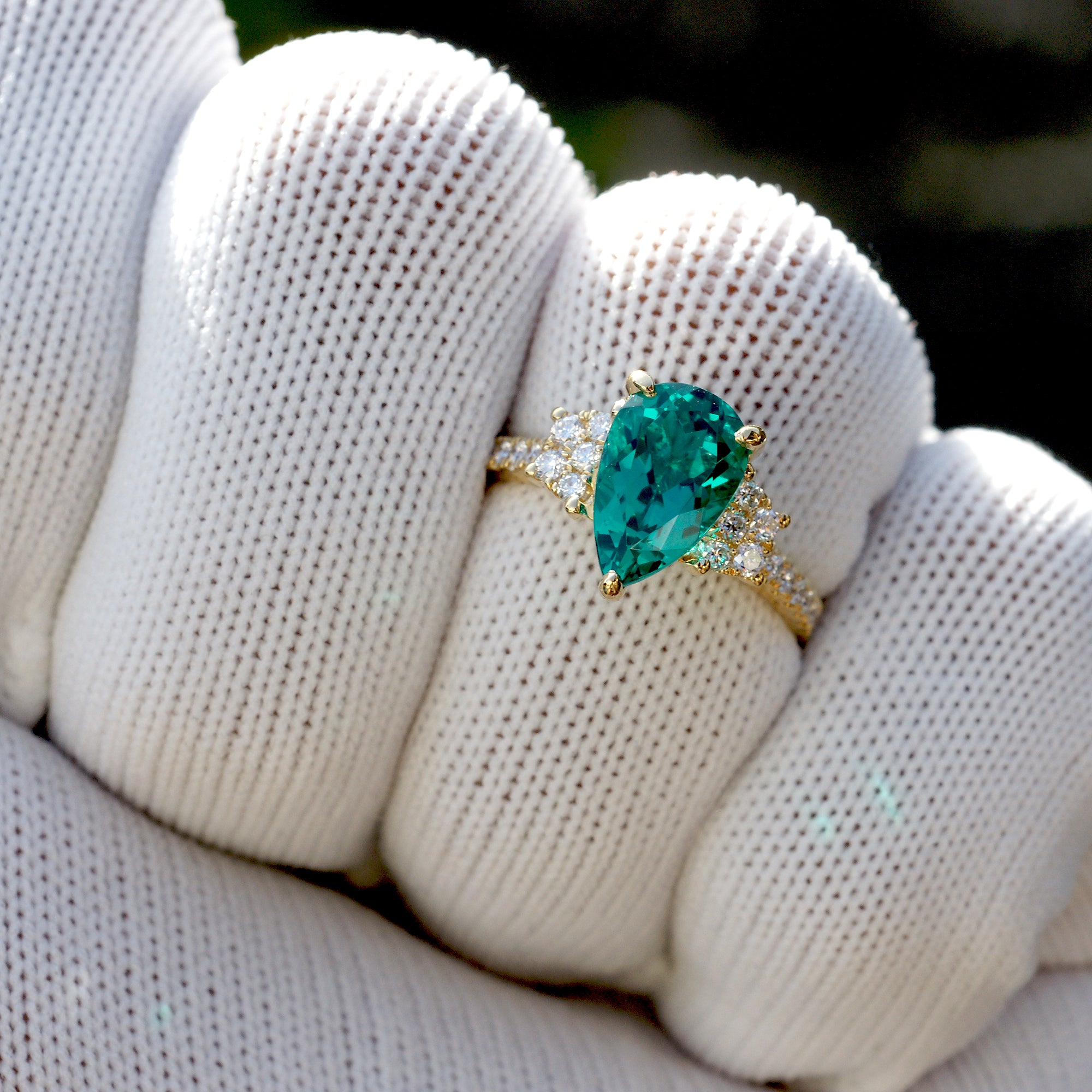 Pear emerald three stone ring with trapezoid side diamond shape in yellow gold