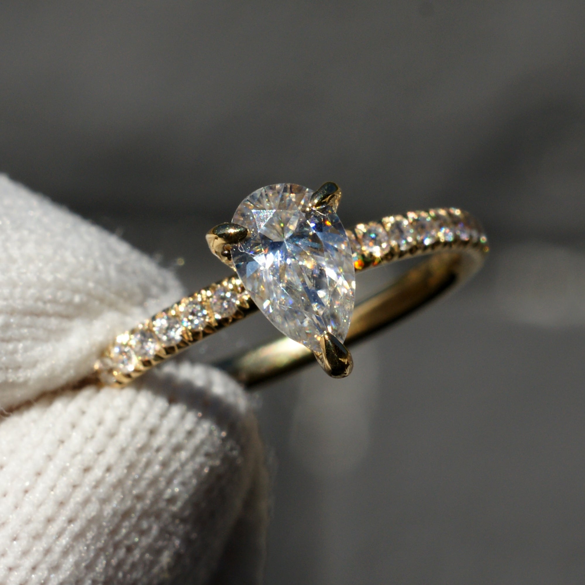 Pear moissanite engagement ring in yellow gold with diamond accent