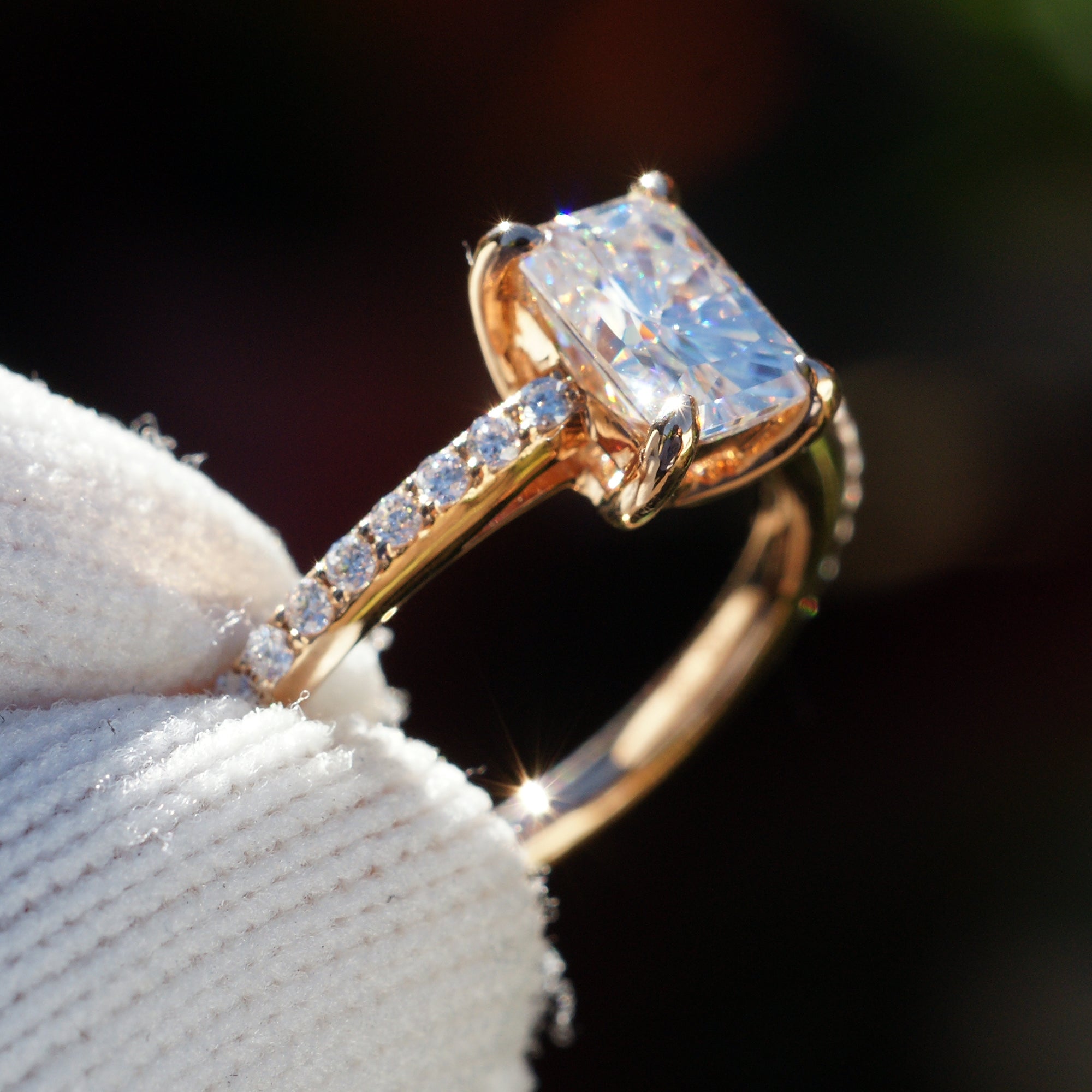Radiant cut moissanite ring in rose gold with diamond accent on band, side view