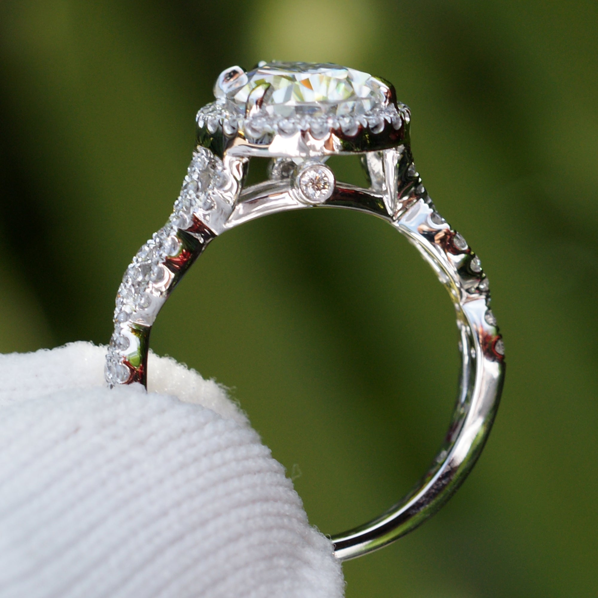 Pear moissanite ring with diamond halo and twisted diamond band in white gold or platinum profile view