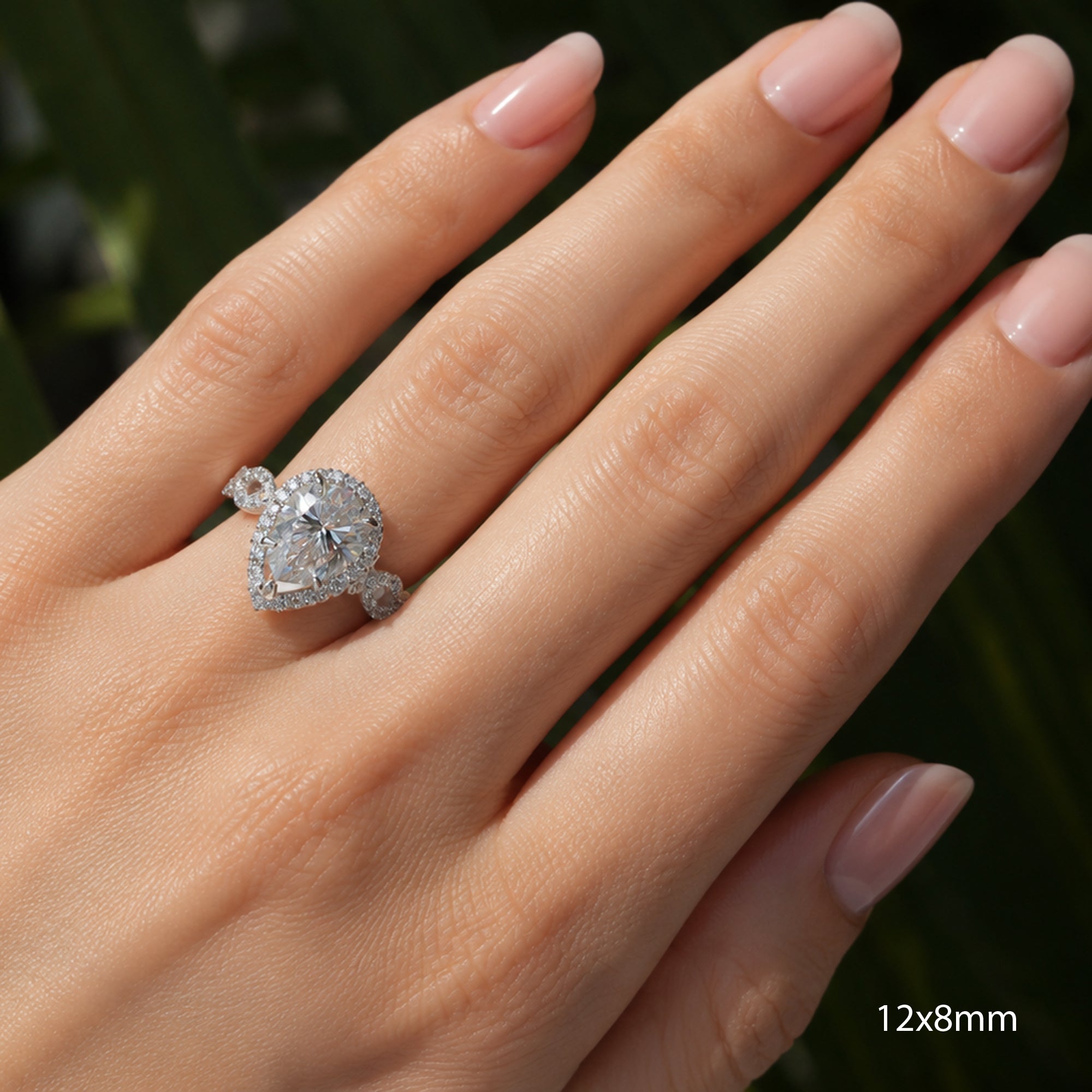 Pear moissanite ring with diamond halo and twisted diamond band in white gold or platinum on a hand