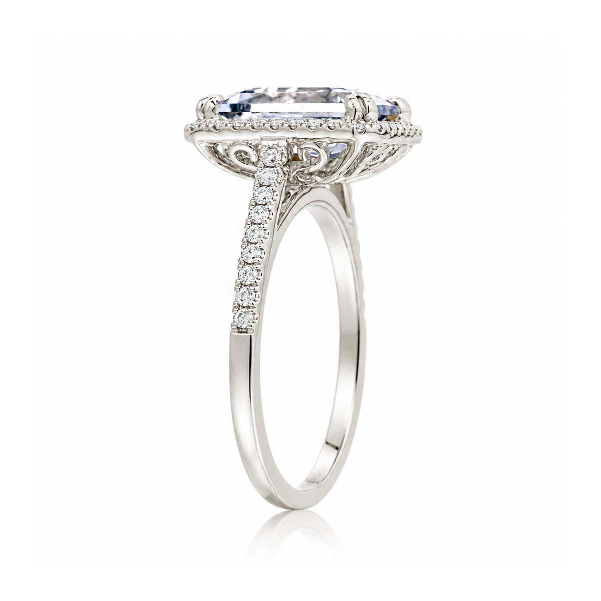 Emerald step cut diamond halo ring with a squarish band and cathedral setting white gold