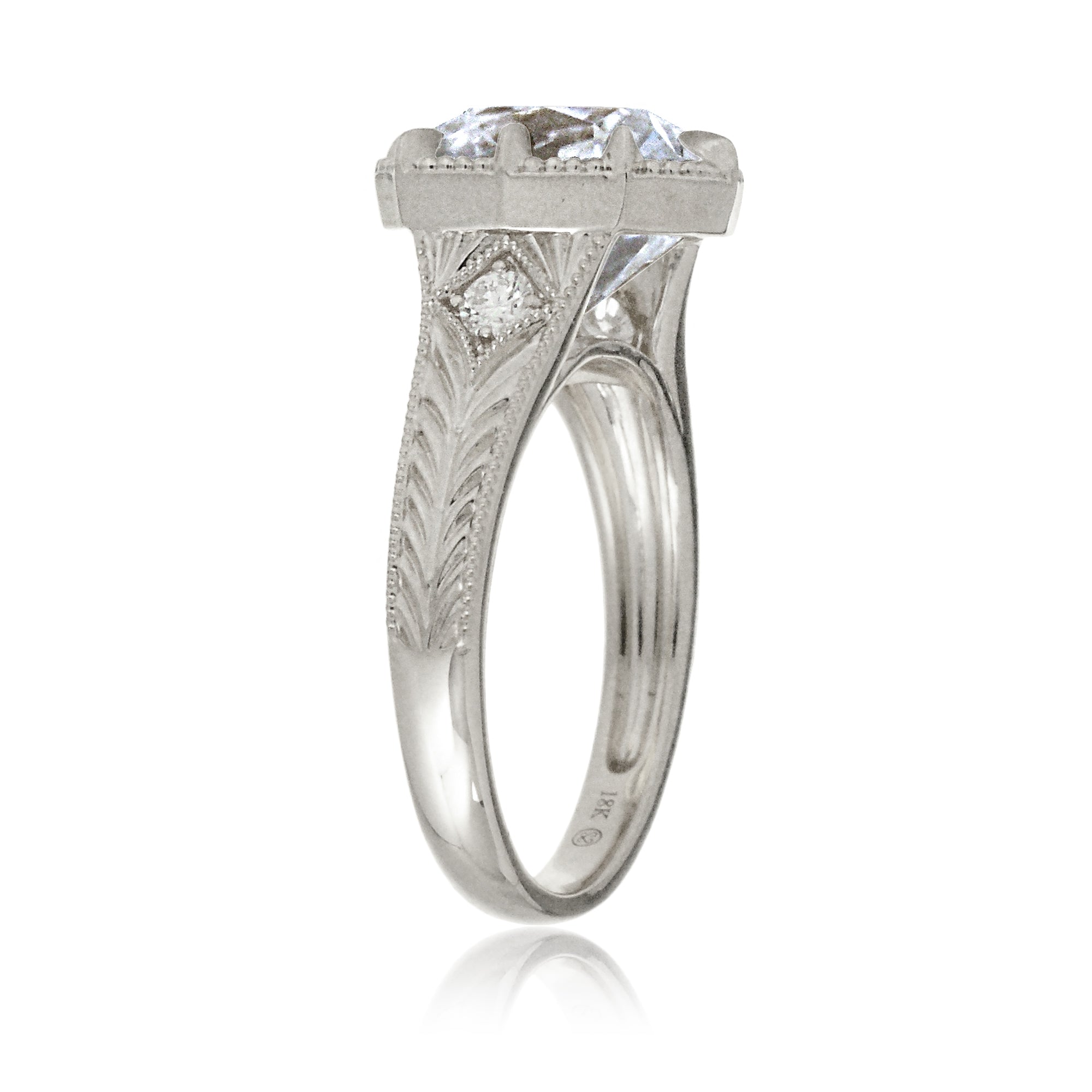 An elegant cushion diamond in an old mine cut takes center stage in this vintage-style ring. The white gold band, adorned with delicate detailing, highlights the diamond’s fire and evokes a sense of classic, enduring romance.