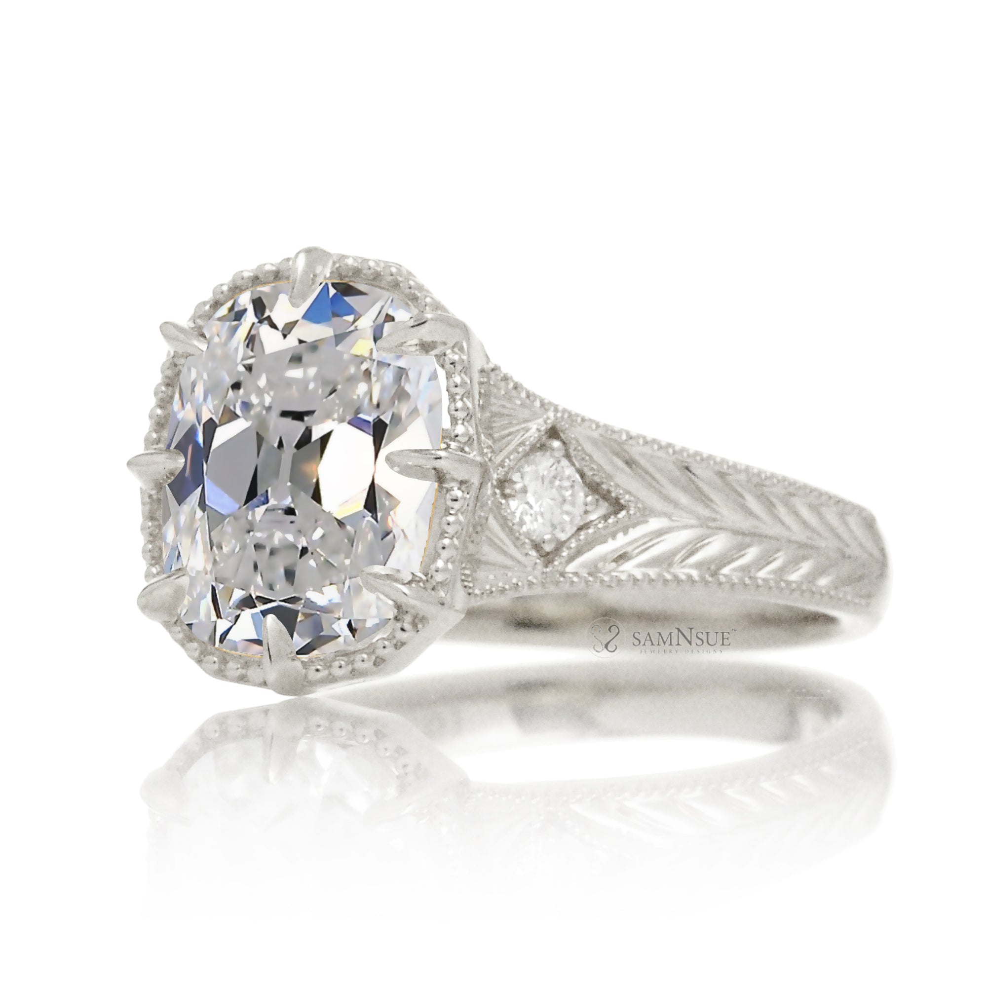 An elegant cushion diamond in an old mine cut takes center stage in this vintage-style ring. The white gold band, adorned with delicate detailing, highlights the diamond’s fire and evokes a sense of classic, enduring romance.