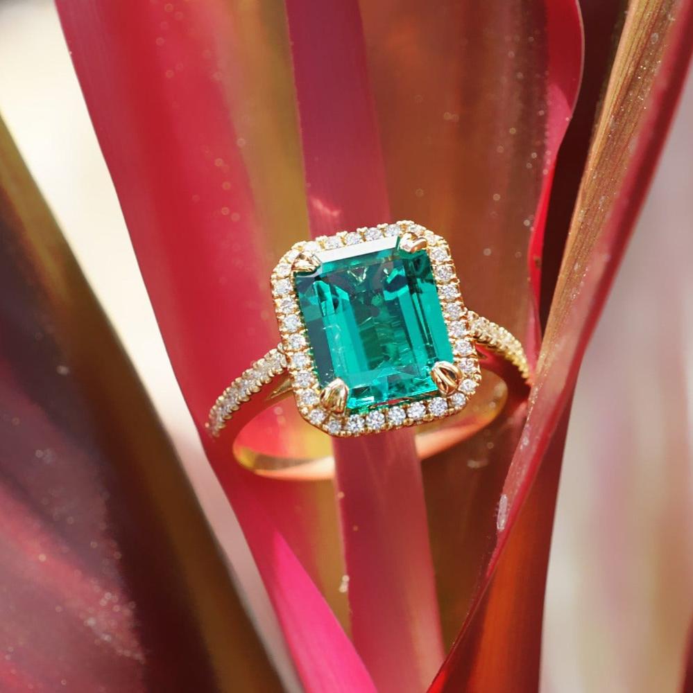 Emerald step cut engagement ring with a diamond halo in yellow gold