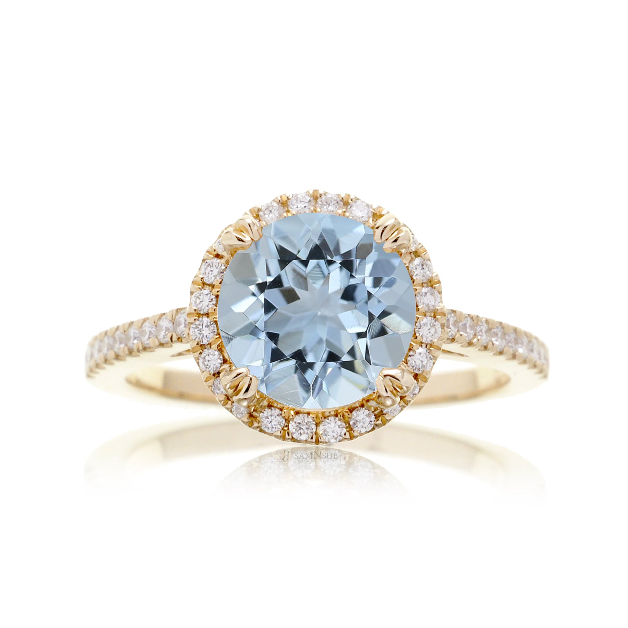 Round aquamarine ring with a diamond halo and cathedral yellow gold setting