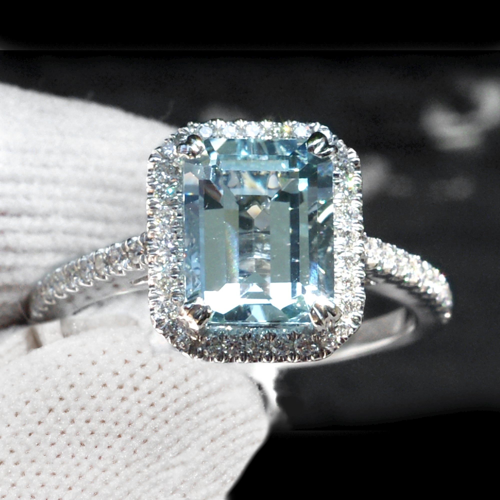 Emerald step cut aquamarine ring with diamond halo and band in white gold