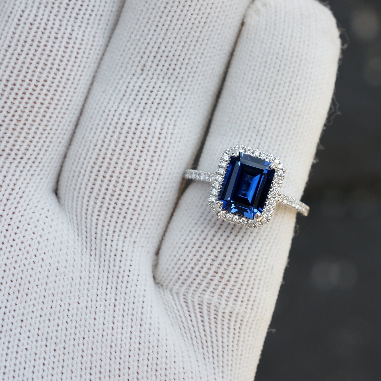 Emerald cut blue sapphire engagement ring with diamond halo and white gold