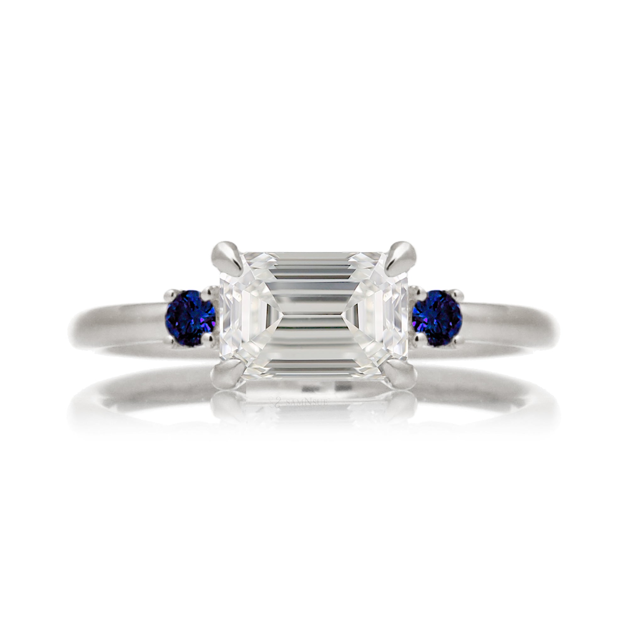 east-west emerald cut diamond three stone ring the Lena with side blue sapphires white gold