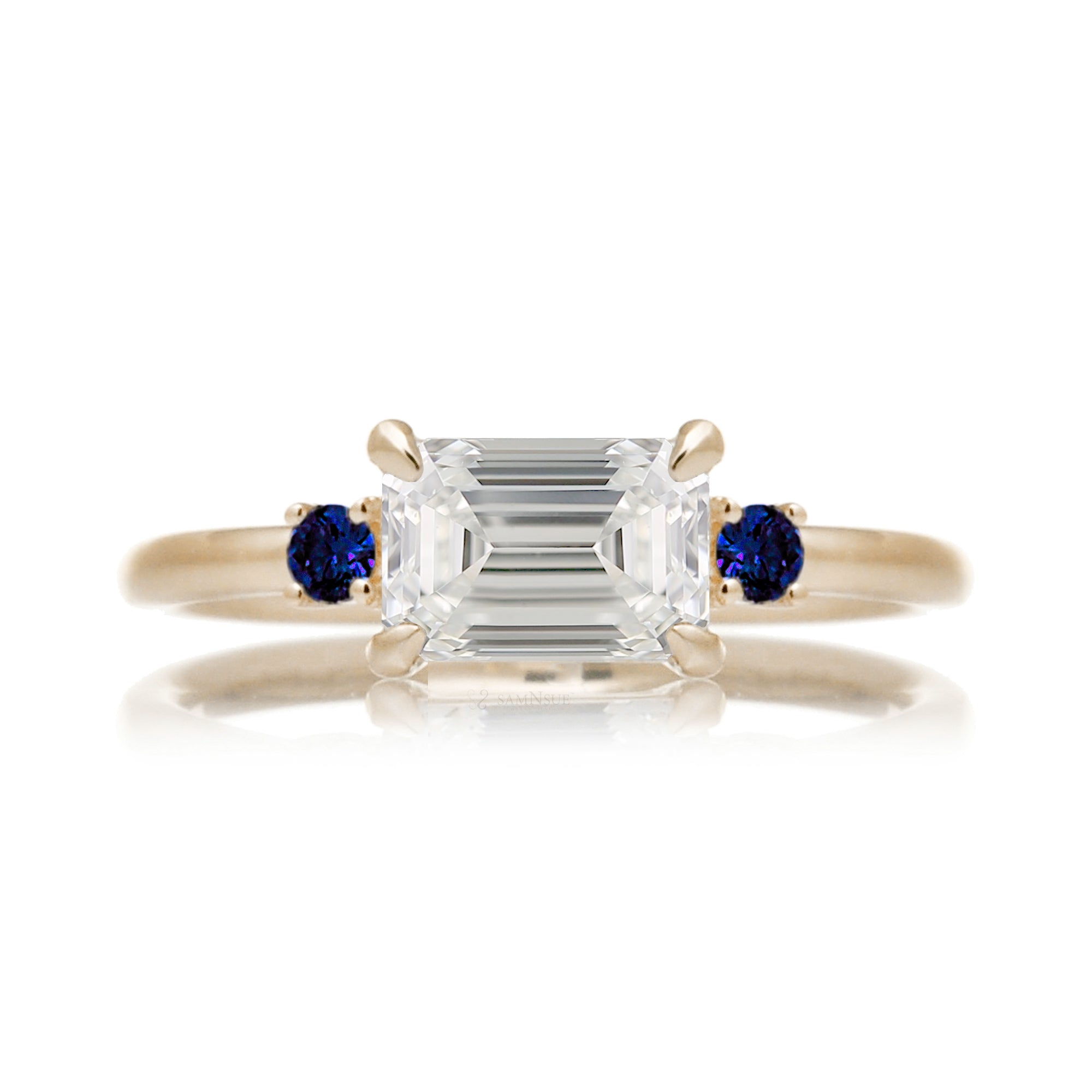 east-west emerald cut diamond three stone ring the Lena with side blue sapphires yellow gold