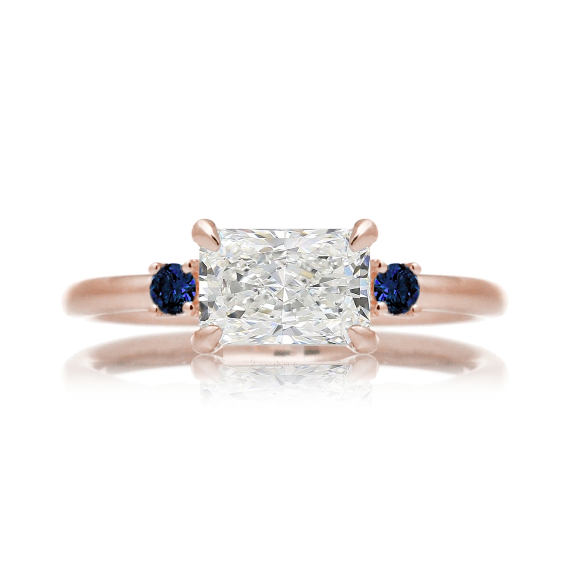 east-west radiant cut lab-grown diamond threestone ring with side blue sapphires rose gold