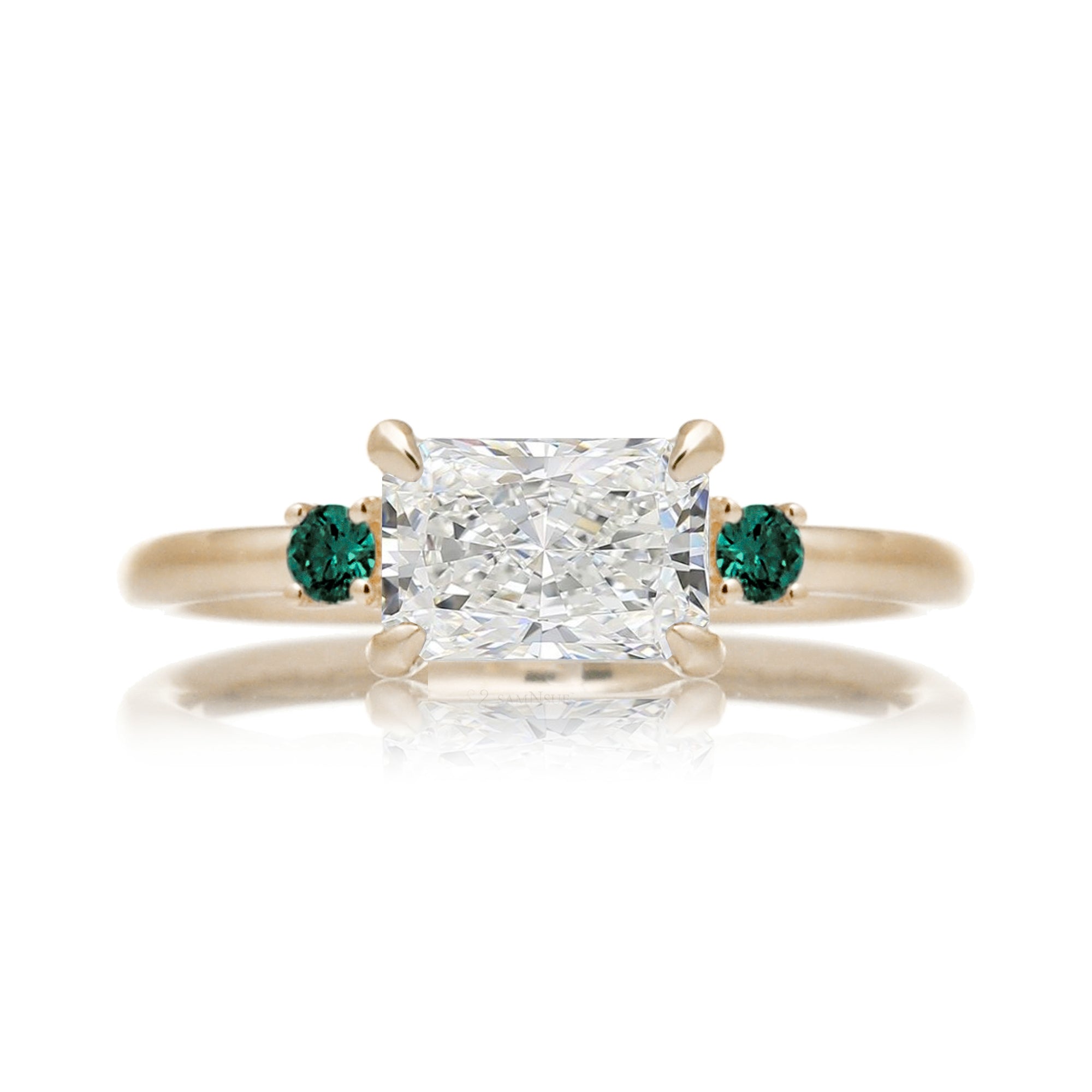 east-west radiant cut lab-grown diamond threestone ring with green emerald yellow gold