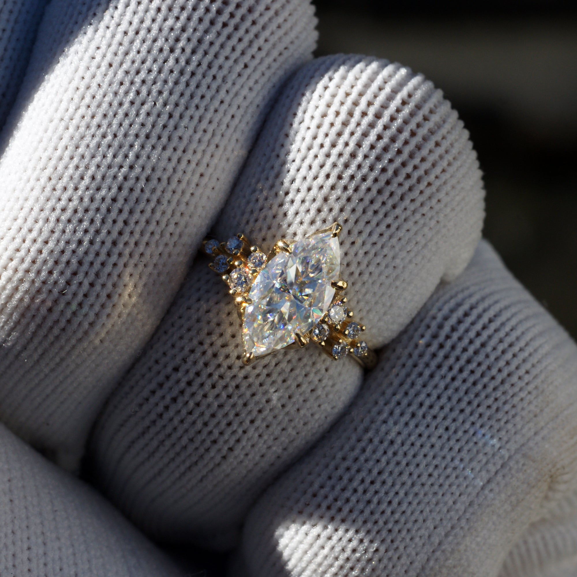 Marquise cut moissanite and diamond engagement ring in the stella yellow gold on finger