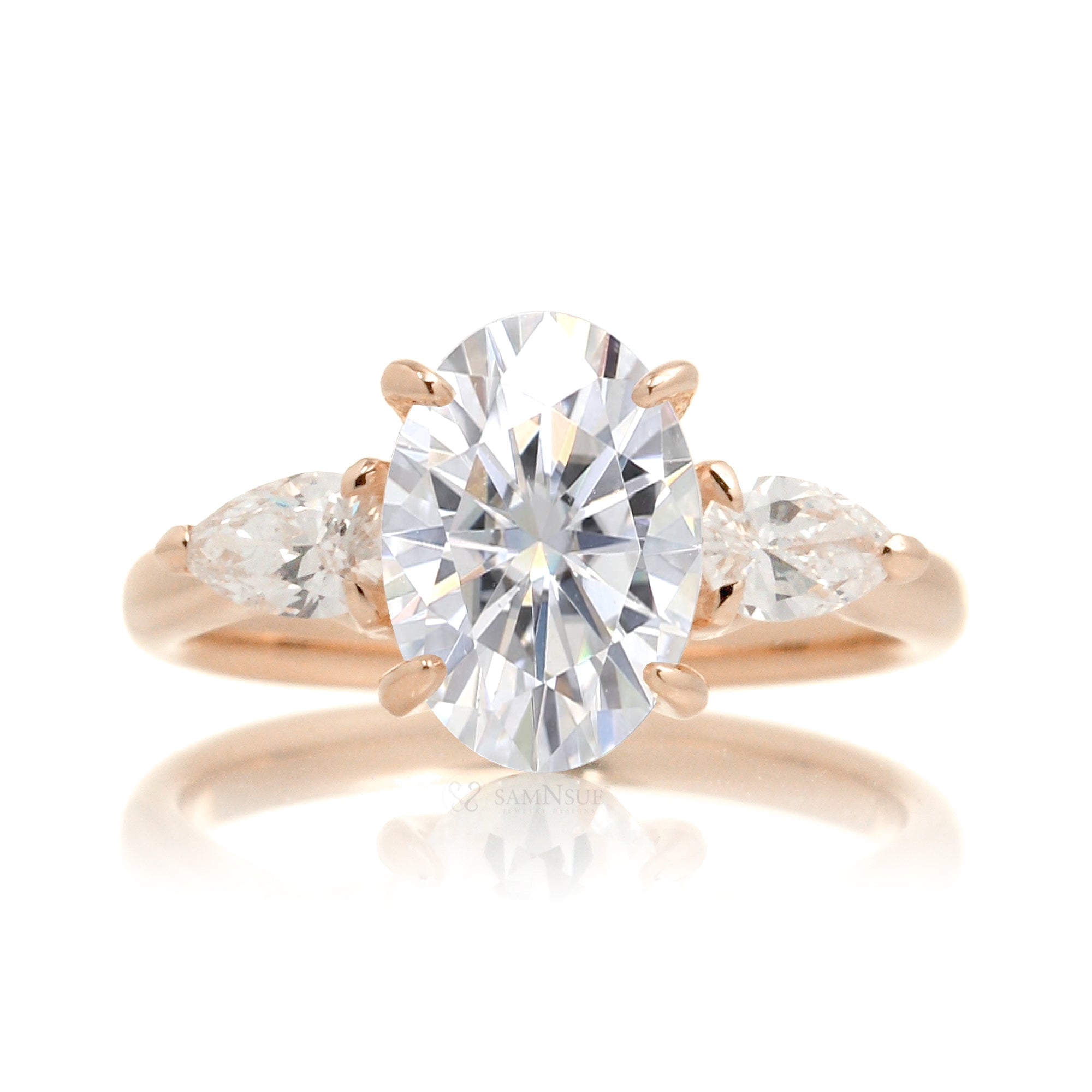 Front view of oval moissanite center stone with pear side stones set in 18k rose gold band