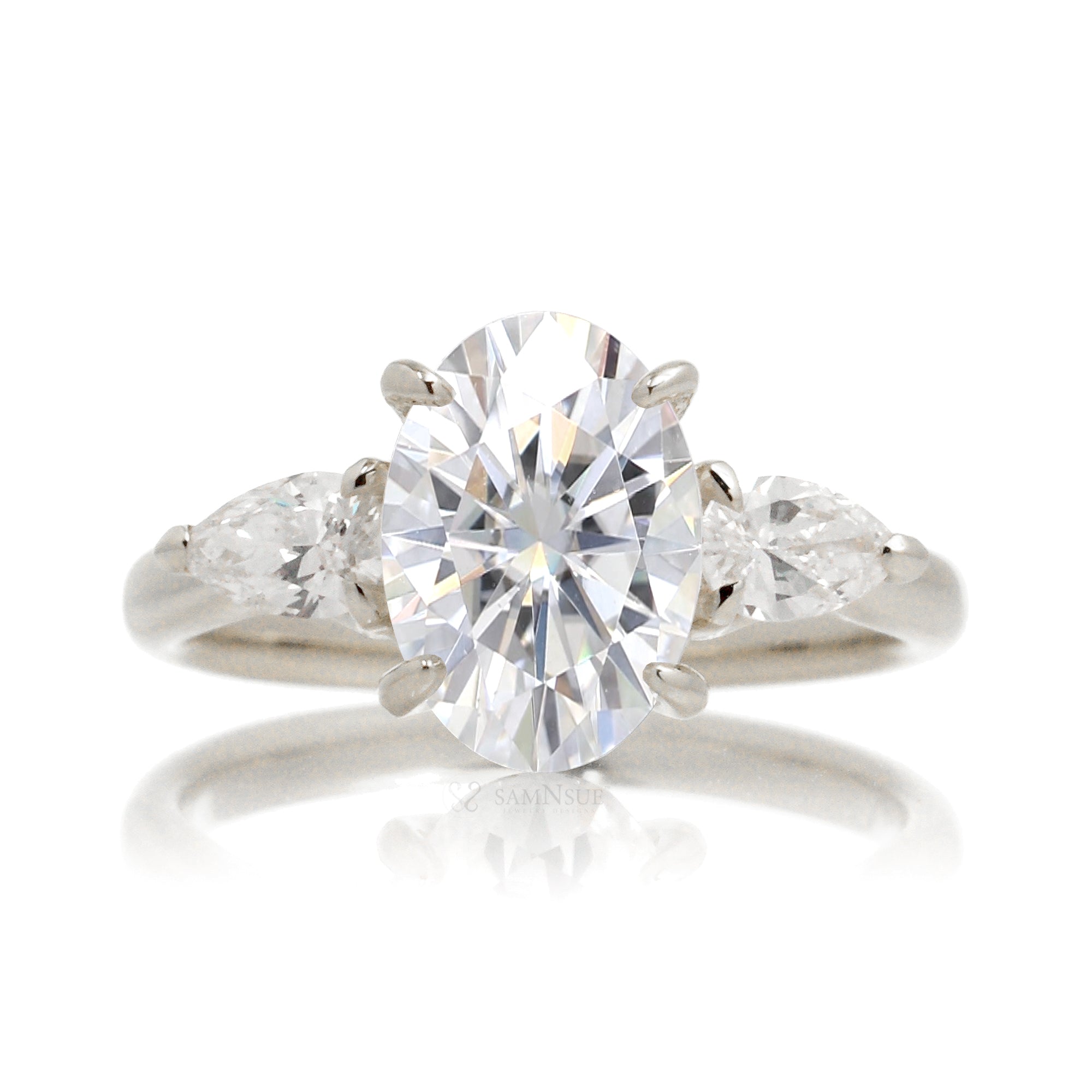 Front view of oval moissanite center stone with pear side stones set in 18k white gold band