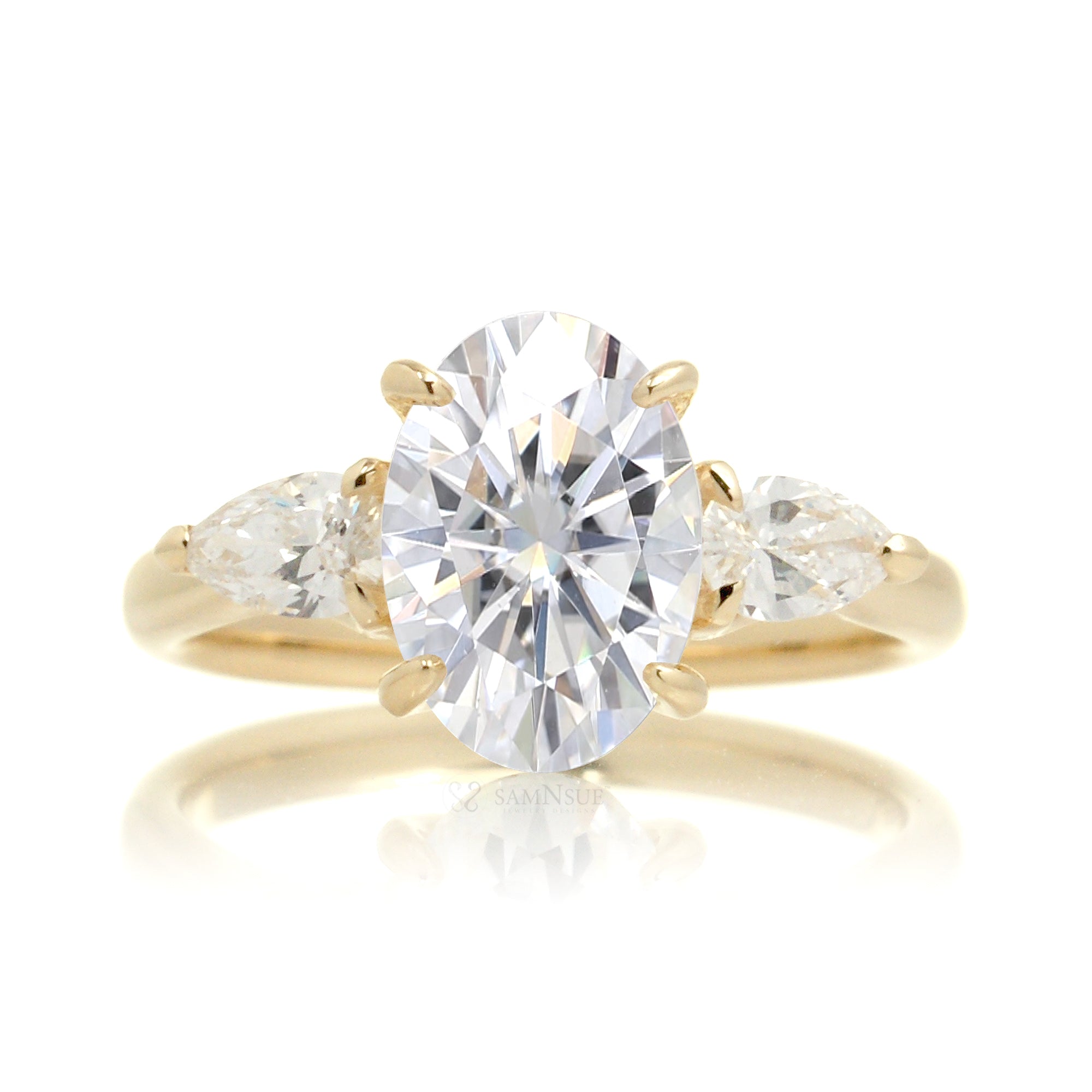Front view of oval moissanite center stone with pear side stones set in 18k yellow gold band