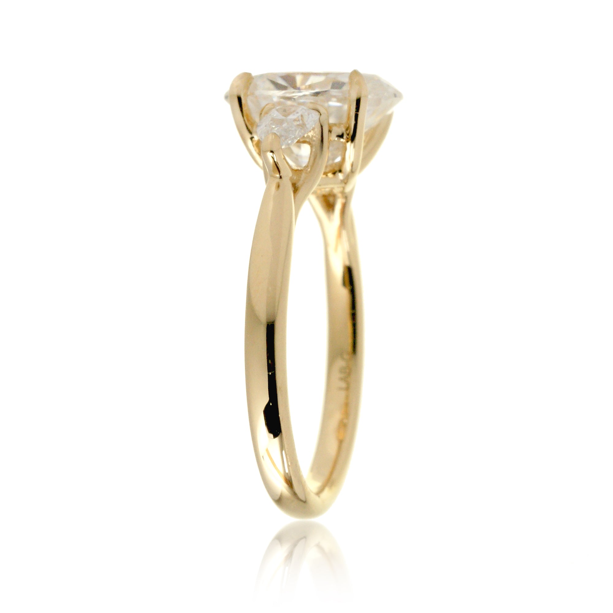 Close-up view of three-stone moissanite ring in 18k yellow gold showing elegant side pear moissanites