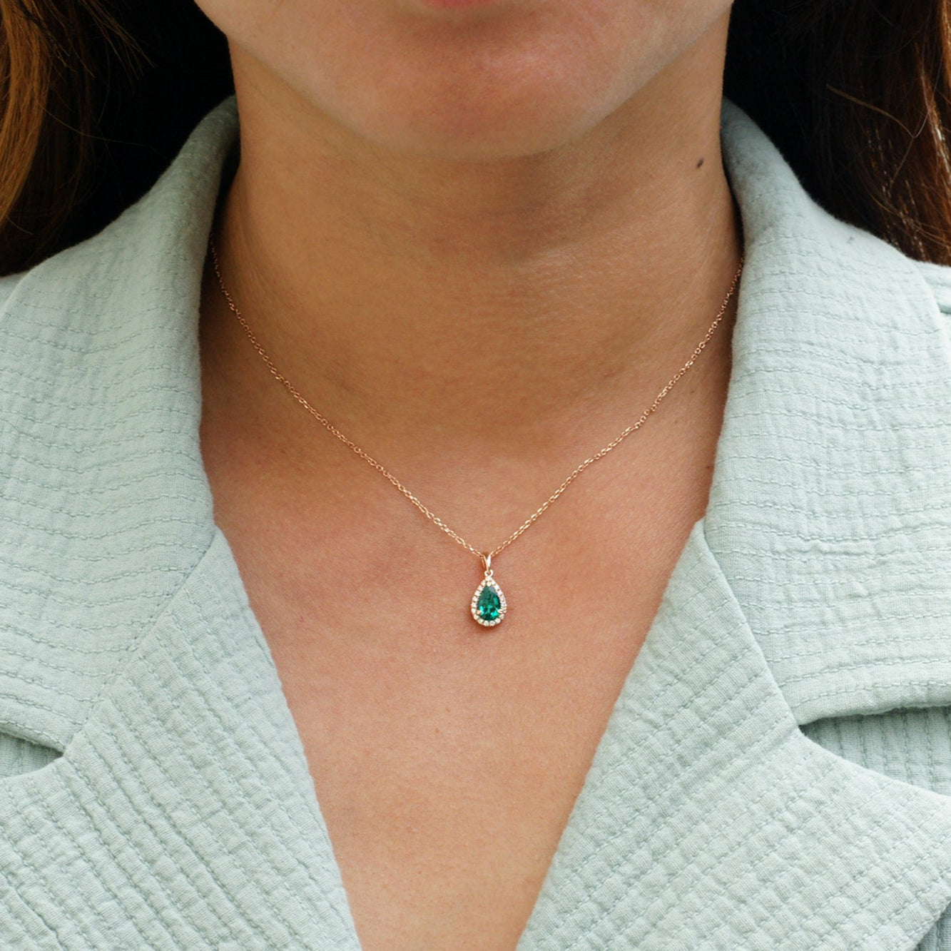 Pear green emerald pendant with diamond halo yellow gold