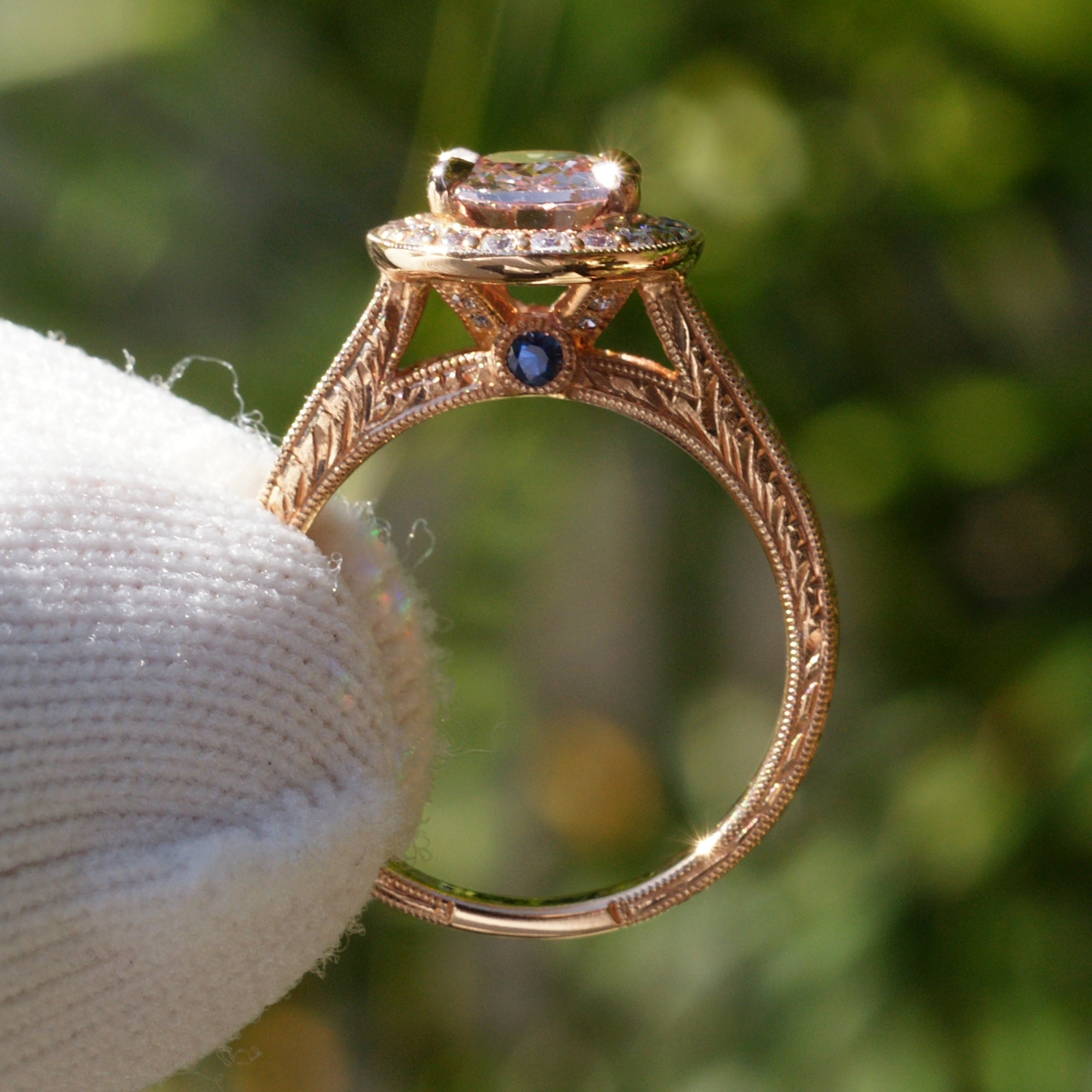 Oval pink sapphire with diamond halo engagement ring on a vintage hand carved rose gold setting