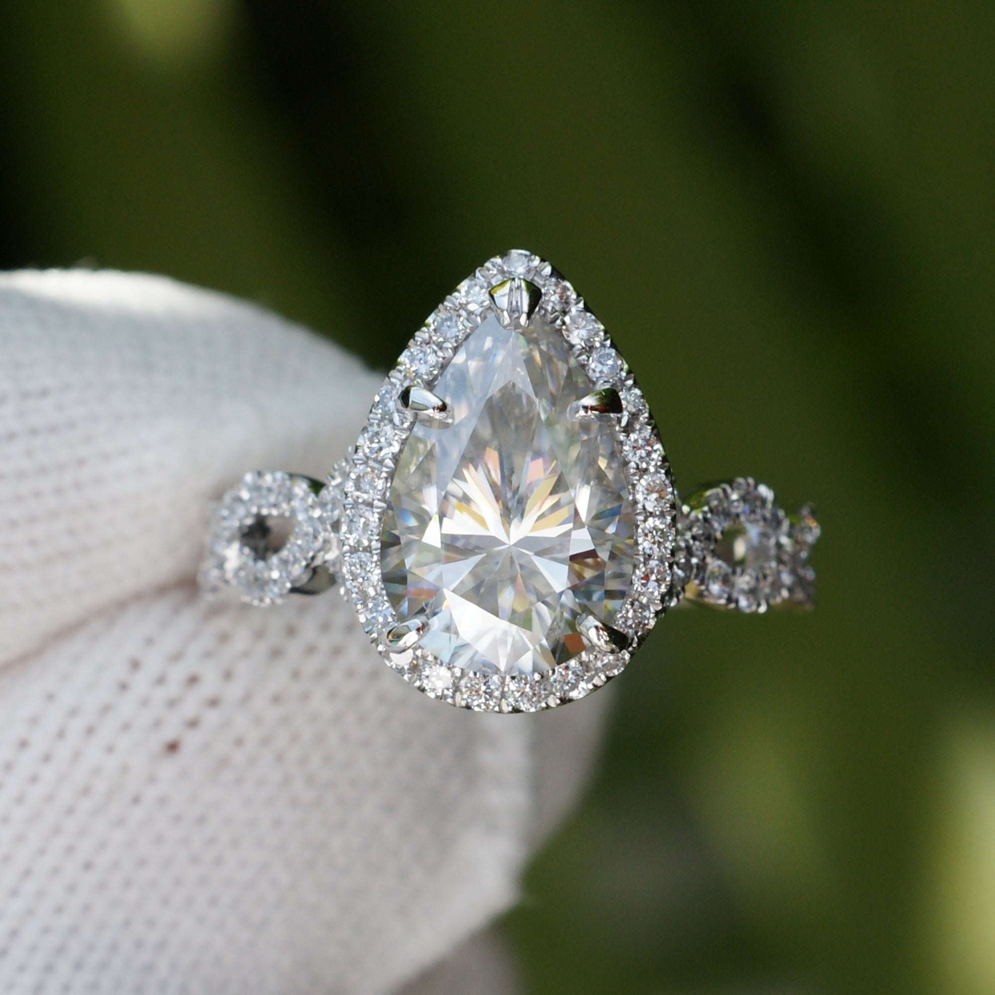 Pear moissanite ring with diamond halo and twisted diamond band in white gold or platinum front view 12x8mm