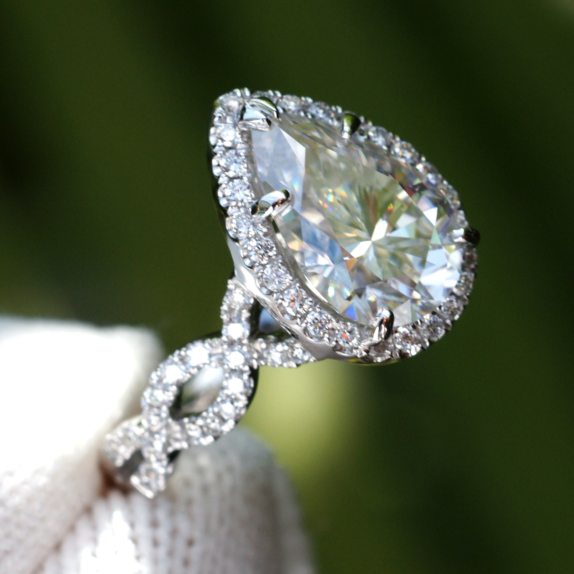 Pear moissanite ring with diamond halo and twisted diamond band in white gold or platinum side view