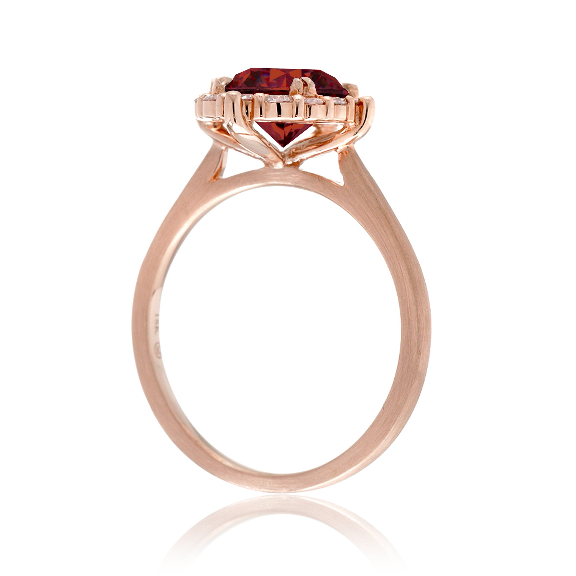 Rose gold ring with a red gemstone on a white background
