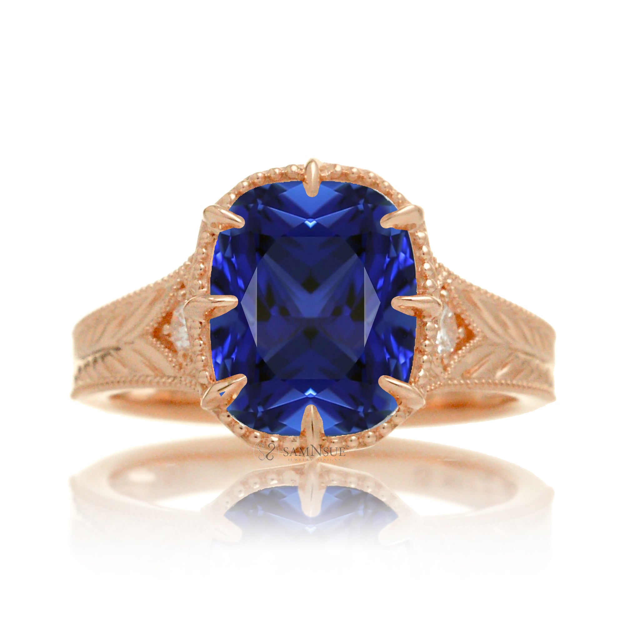 A cushion cut blue sapphire glimmers at the heart of this vintage-inspired engagement ring, set in polished rose gold. The detailed band features hand-carved artistry, enhancing the antique character and timeless appeal.