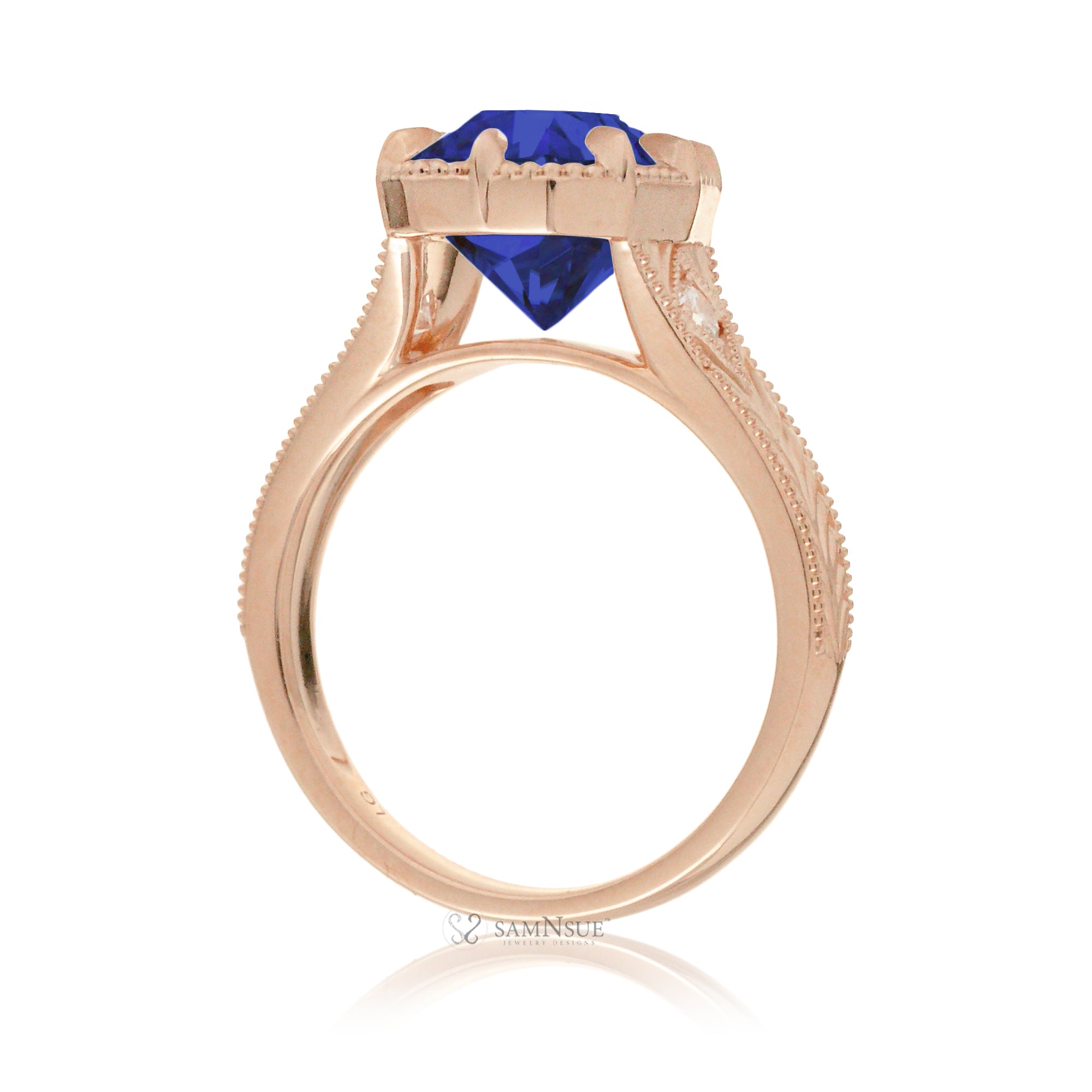 A cushion cut blue sapphire glimmers at the heart of this vintage-inspired engagement ring, set in polished rose gold. The detailed band features hand-carved artistry, enhancing the antique character and timeless appeal.