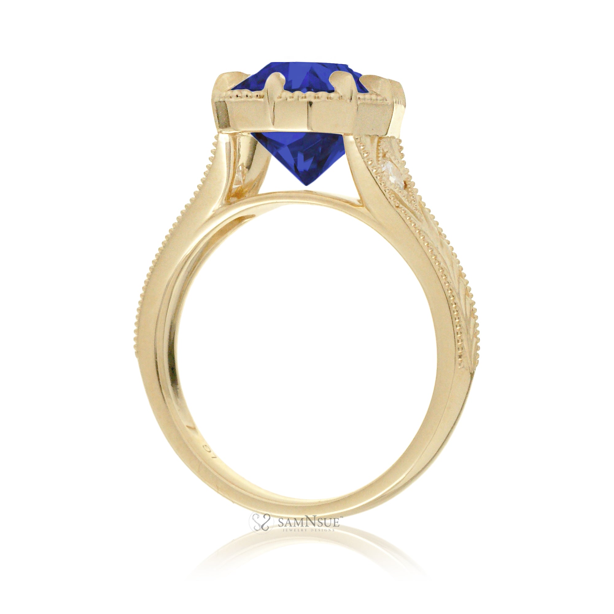 A cushion cut blue sapphire glimmers at the heart of this vintage-inspired engagement ring, set in polished yellow gold. The detailed band features hand-carved artistry, enhancing the antique character and timeless appeal.