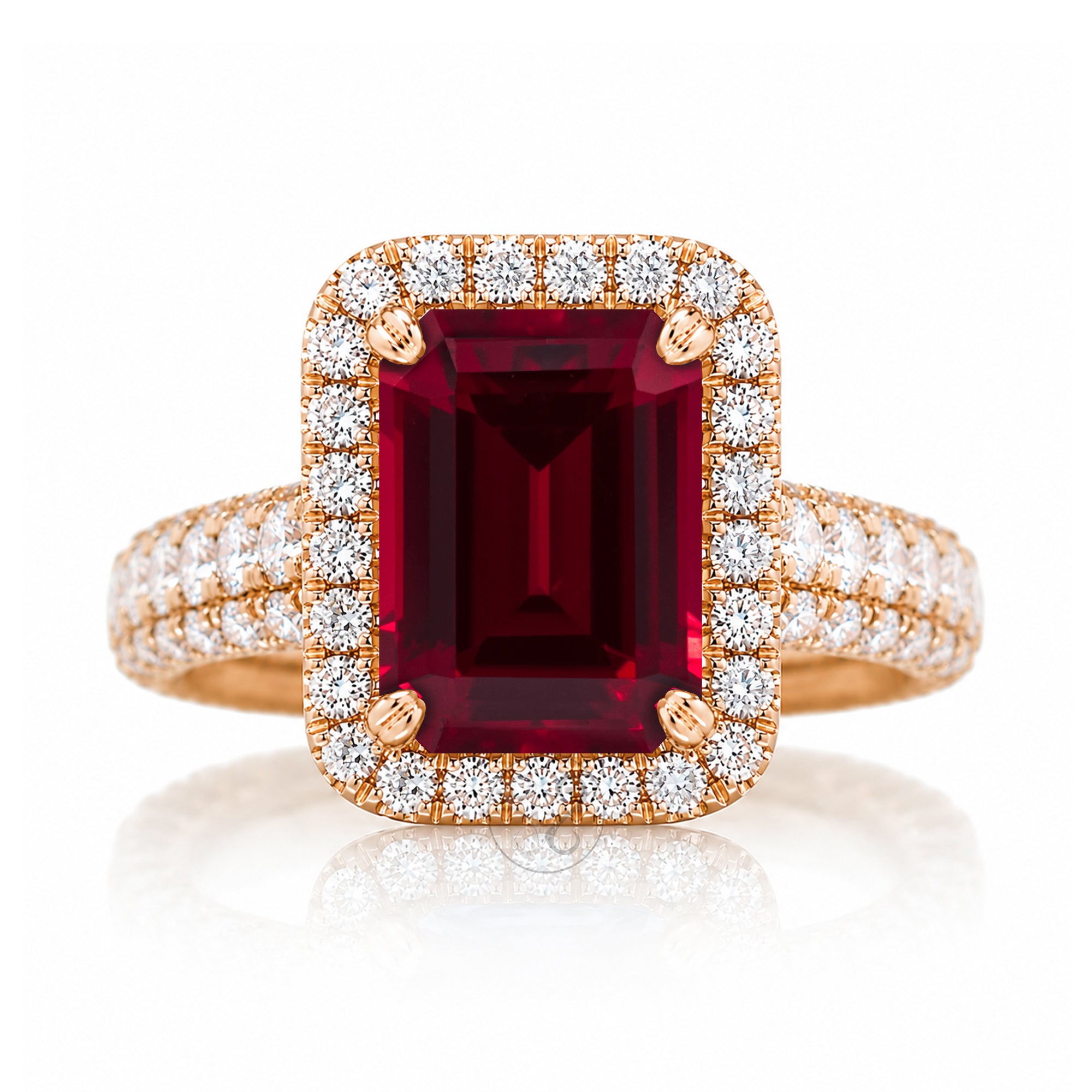 A yellow gold ring featuring a large rectangular emerald-cut deep red ruby center stone, surrounded by a double halo of round brilliant-cut diamonds, with the diamond-set band extending on either side, set against a clean white background with a soft reflection.