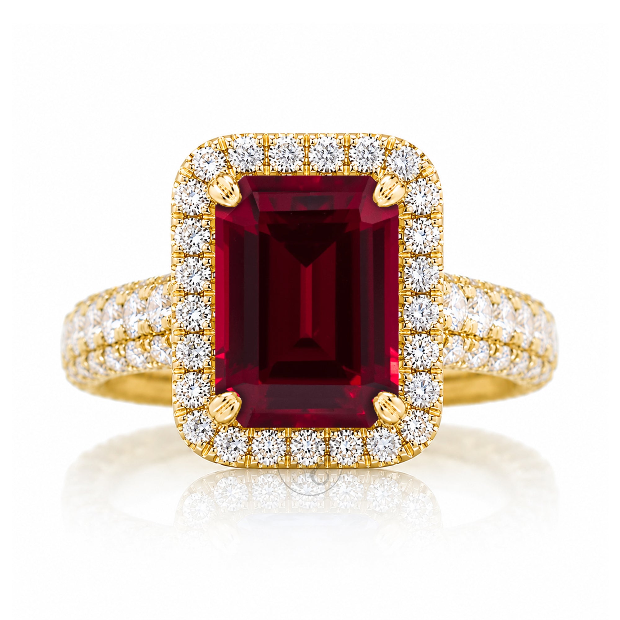 A yellow gold ring featuring a large rectangular emerald-cut deep red ruby center stone, surrounded by a double halo of round brilliant-cut diamonds, with the diamond-set band extending on either side, set against a clean white background with a soft reflection.