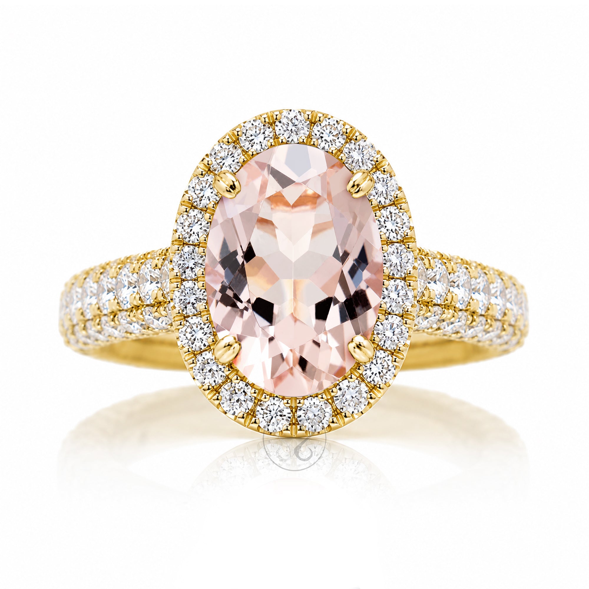 An oval-cut pink morganite halo ring in yellow gold, featuring a central peach-pink gemstone surrounded by a double halo of small clear stones and a diamond pavé band The Tamara