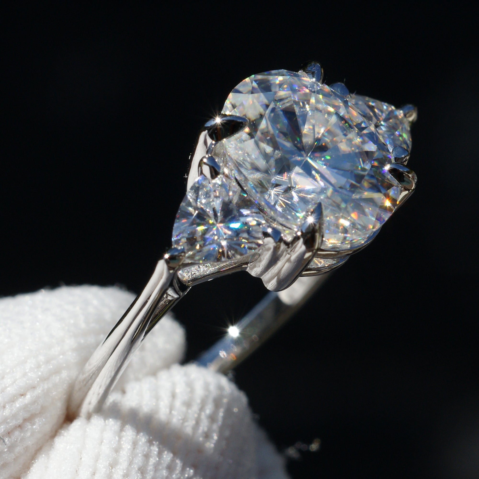 Oval moissanite three stone ring with trillion on each side in white gold