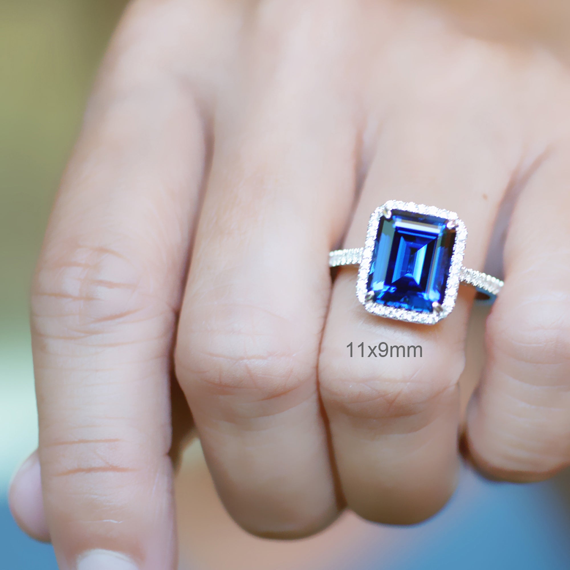 Emerald cut sapphire engagement ring with a diamond halo in white gold