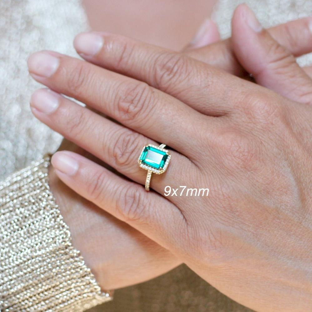 Emerald step cut engagement ring with a diamond halo in yellow gold